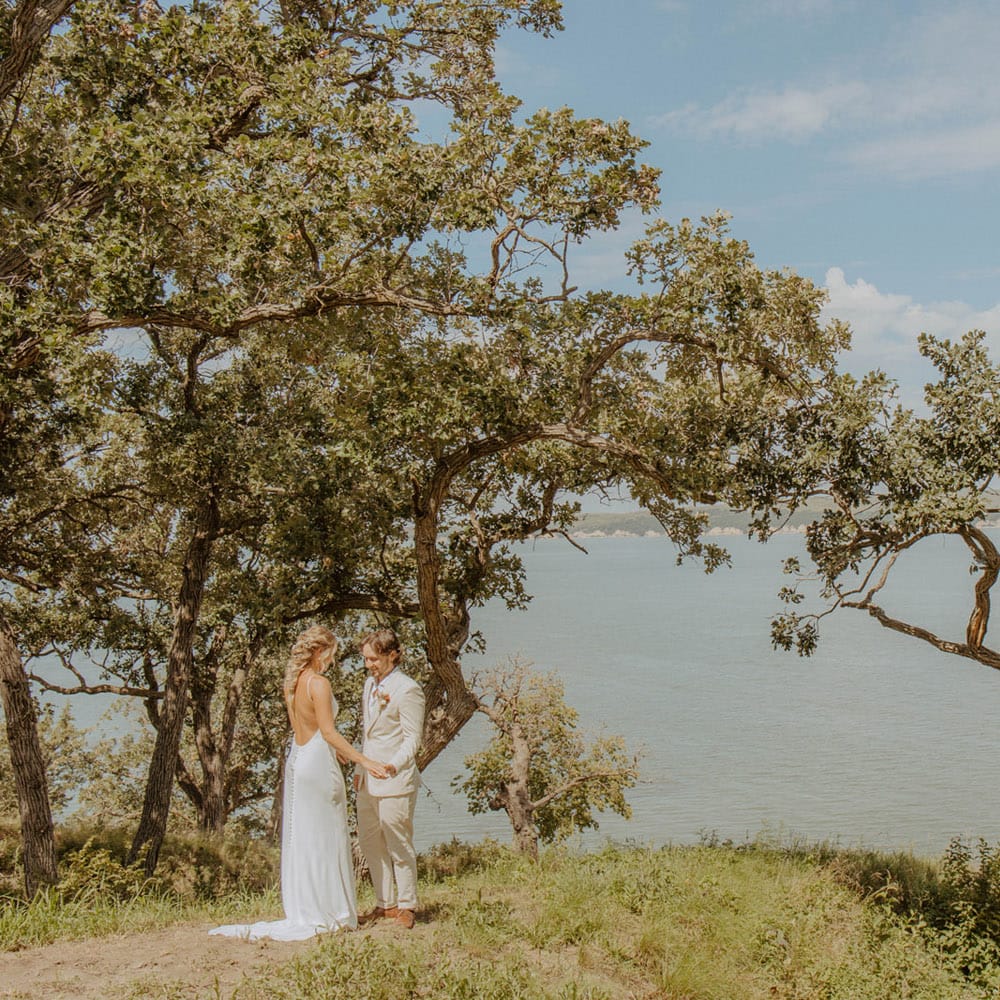 Bride and groom share an embrace lakeside