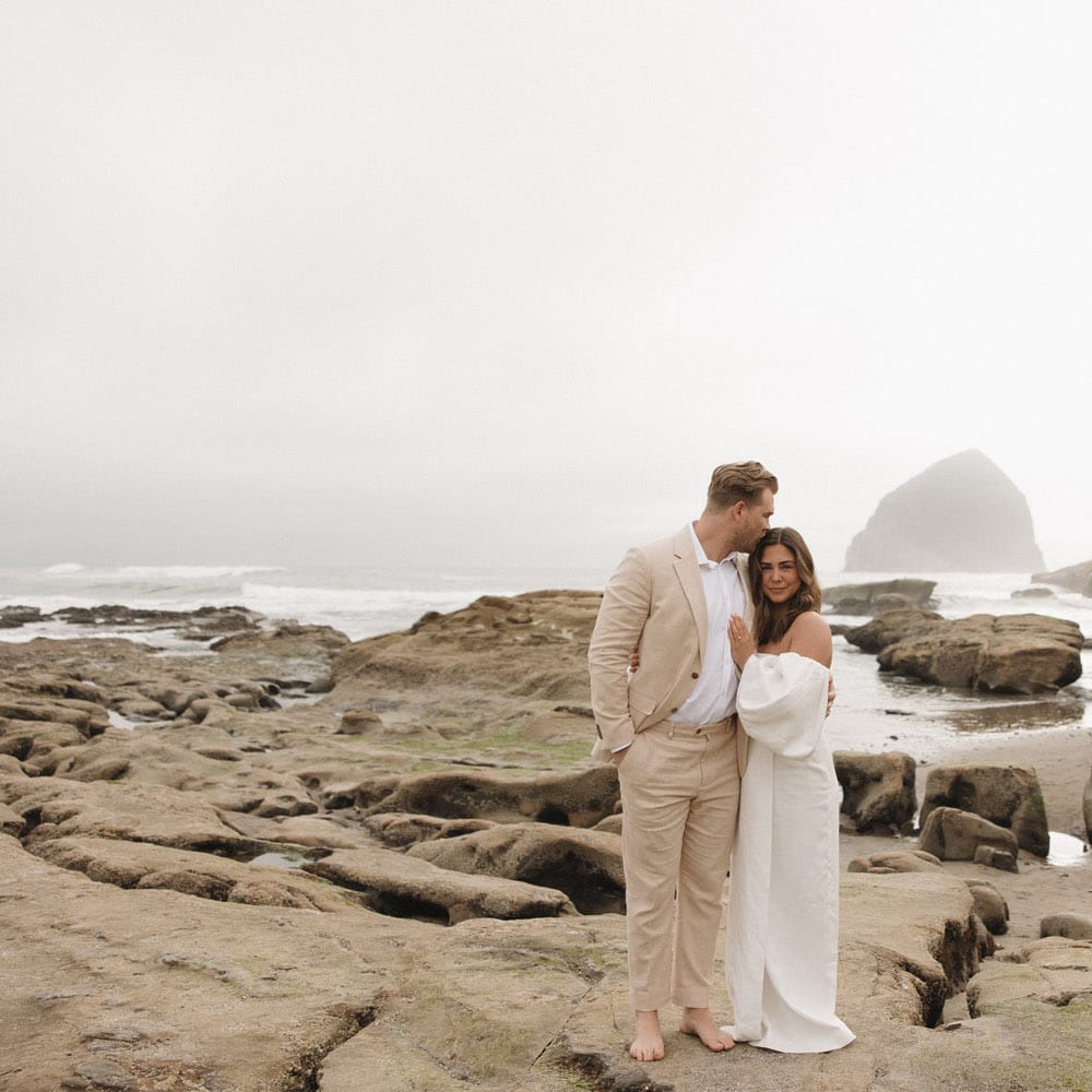 Bride and groom cozy up on the rocks of the Oregon coast