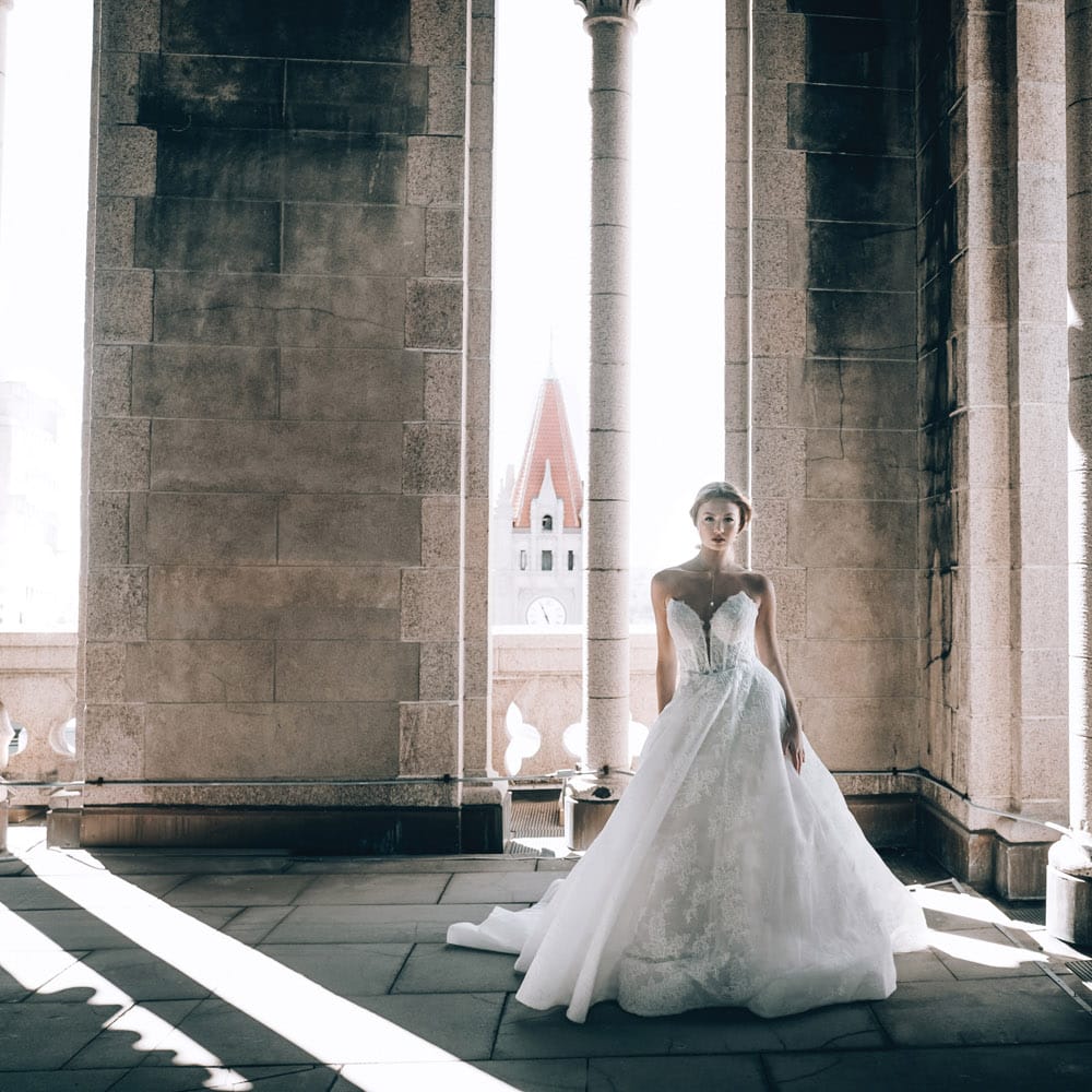 Model in lace ballgown poses in Landmark Center venue
