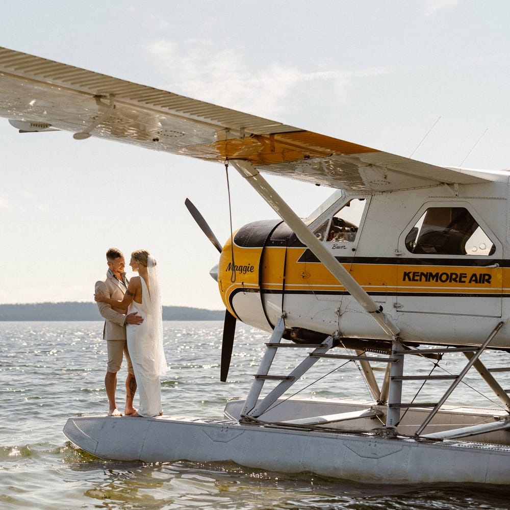 Bride and groom share a kiss next to seaplane off Orcas Island for elopement