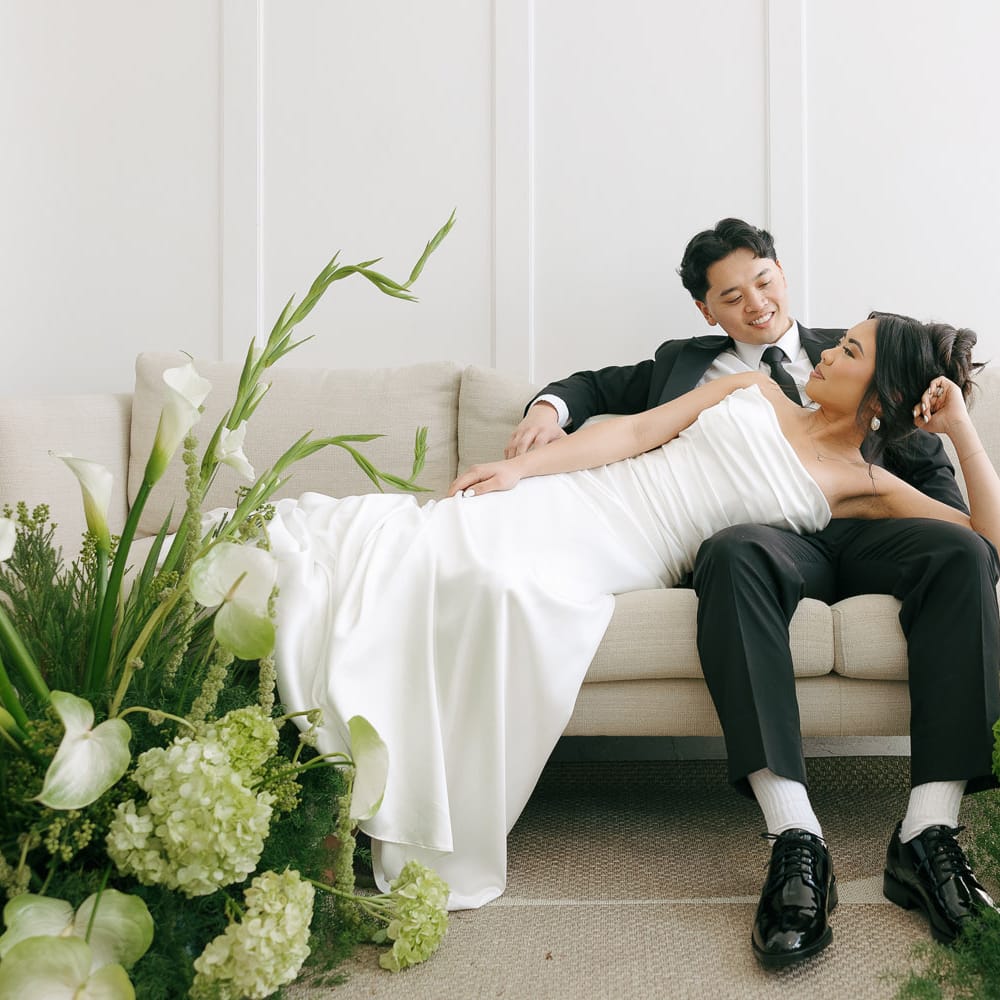 Models Lounge on Couch Surrounded by Lush Green Florals in Styled Shoot at 210 Seattle