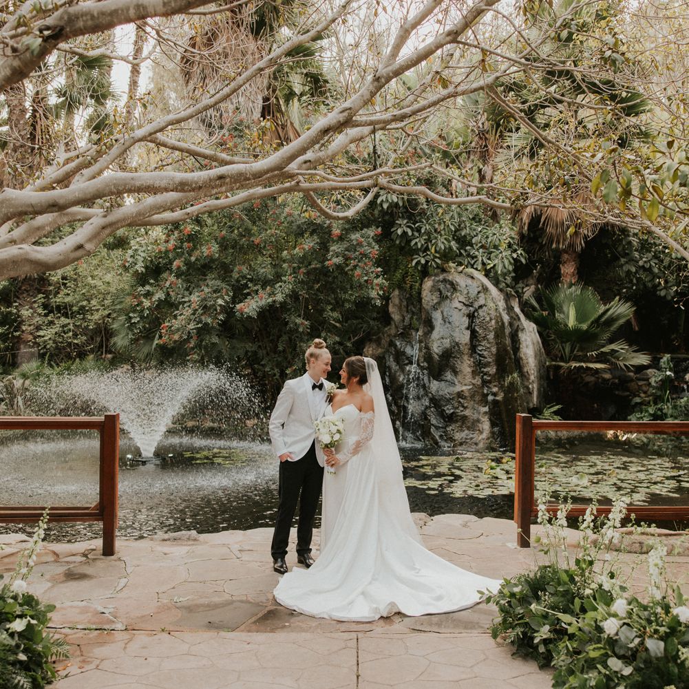 Taylor and Summer embrace on the grounds of Botanica on their wedding day
