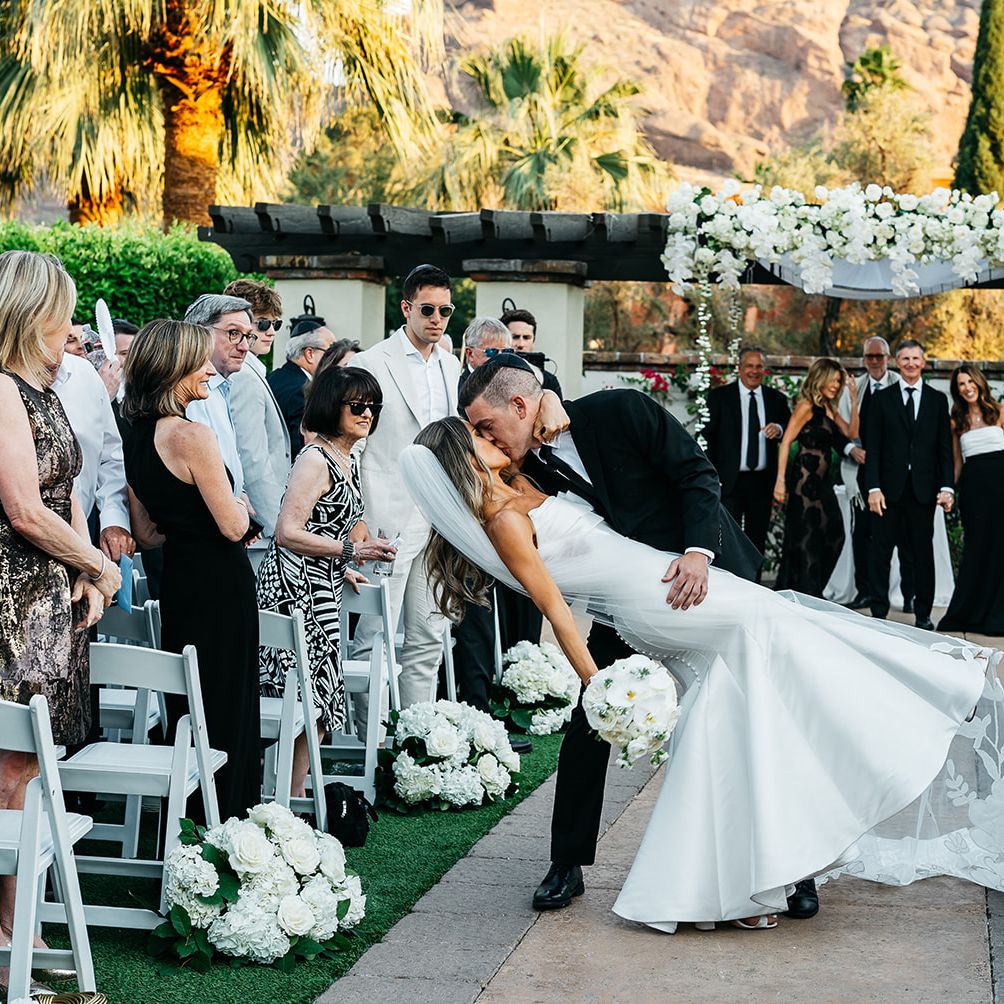Groom dips bride into kiss at the end of floral-lined aisle at The Omni Scottsdale Montelucia
