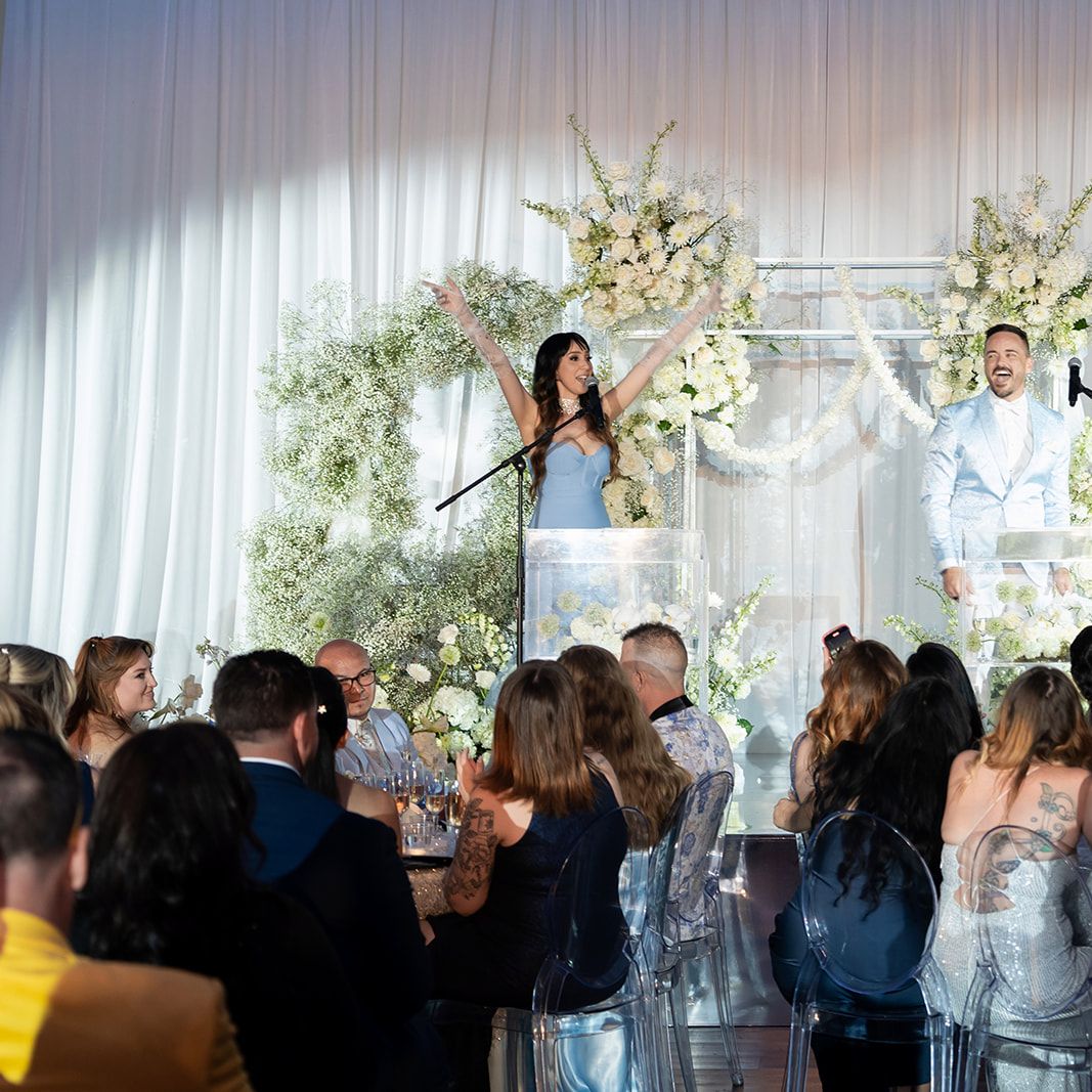 Weddings Royale emcees present on stage in front of a white floral arch and cheering audience at the California Wedding Day Best of 2025 awards ceremony