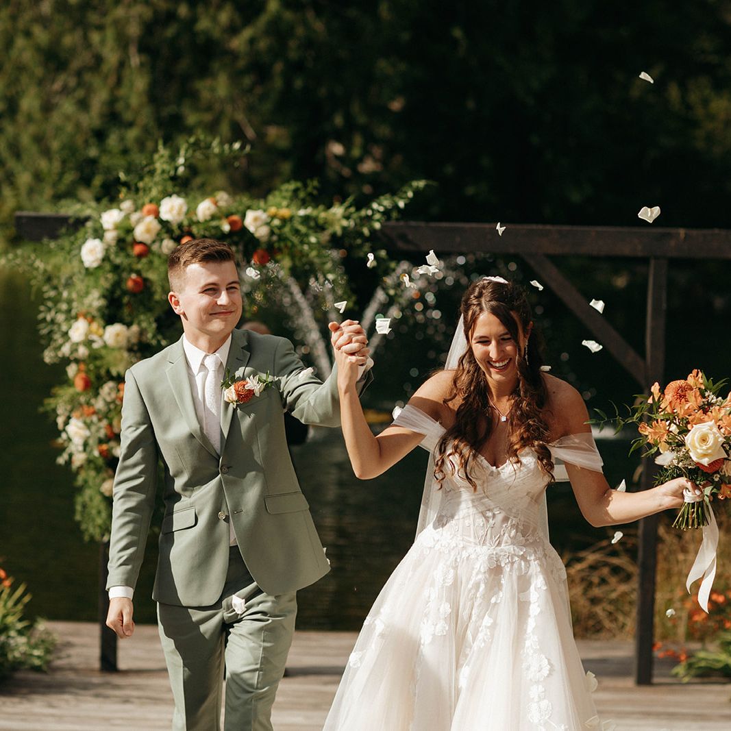 Bride and Groom hold hands and smile while walking back down the aisle