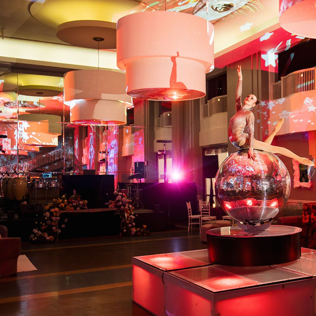 Entertainer balances on disco ball in lively, colorful reception at The Beach Club