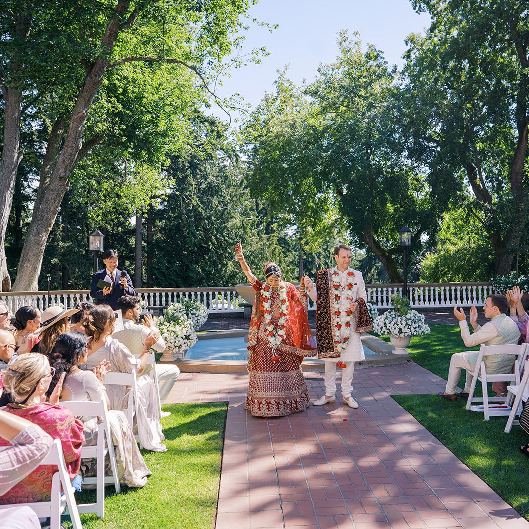 Bride and groom raise their hands in celebration while walking back down the aisle in outdoor ceremony at Lairmont Manor