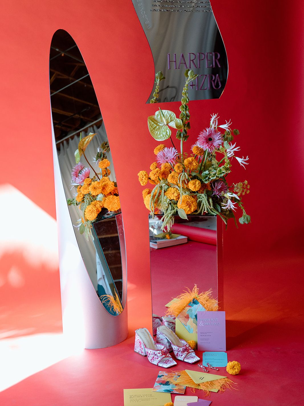 Bold maximalist wedding display with orange and pink florals, sculptural mirrors, colorful stationery and floral bridal shoes