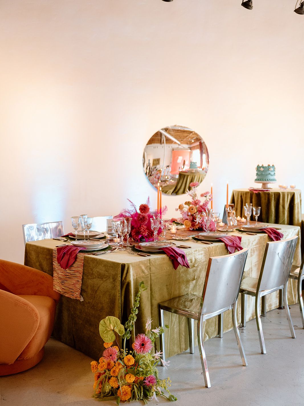 Maximalist wedding tablescape with olive green velvet linens, pink and orange florals, colorful napkins and metallic chairs