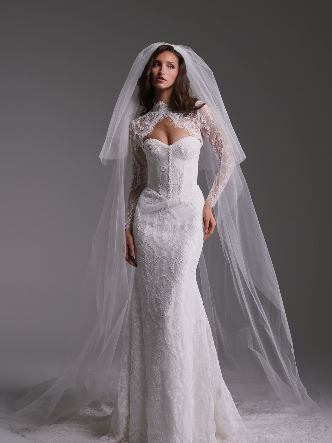 Guillermo Pharis Blanche wedding gown from the Fall 2027 Everlasting collection, with a sheer high-neck lace overlay, long sleeves and fitted silhouette.