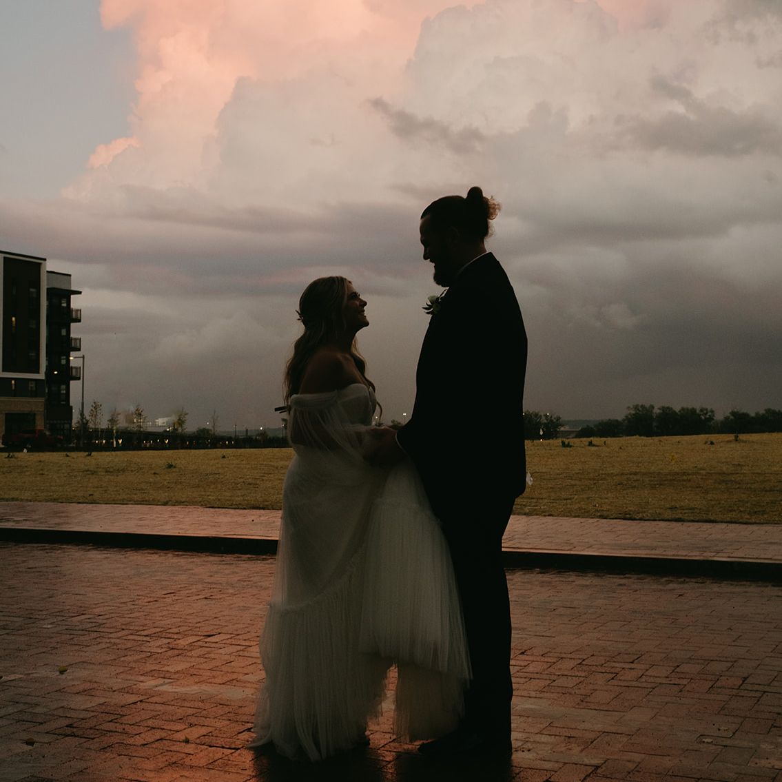 bride and groom backlit by stormy clouded sunset