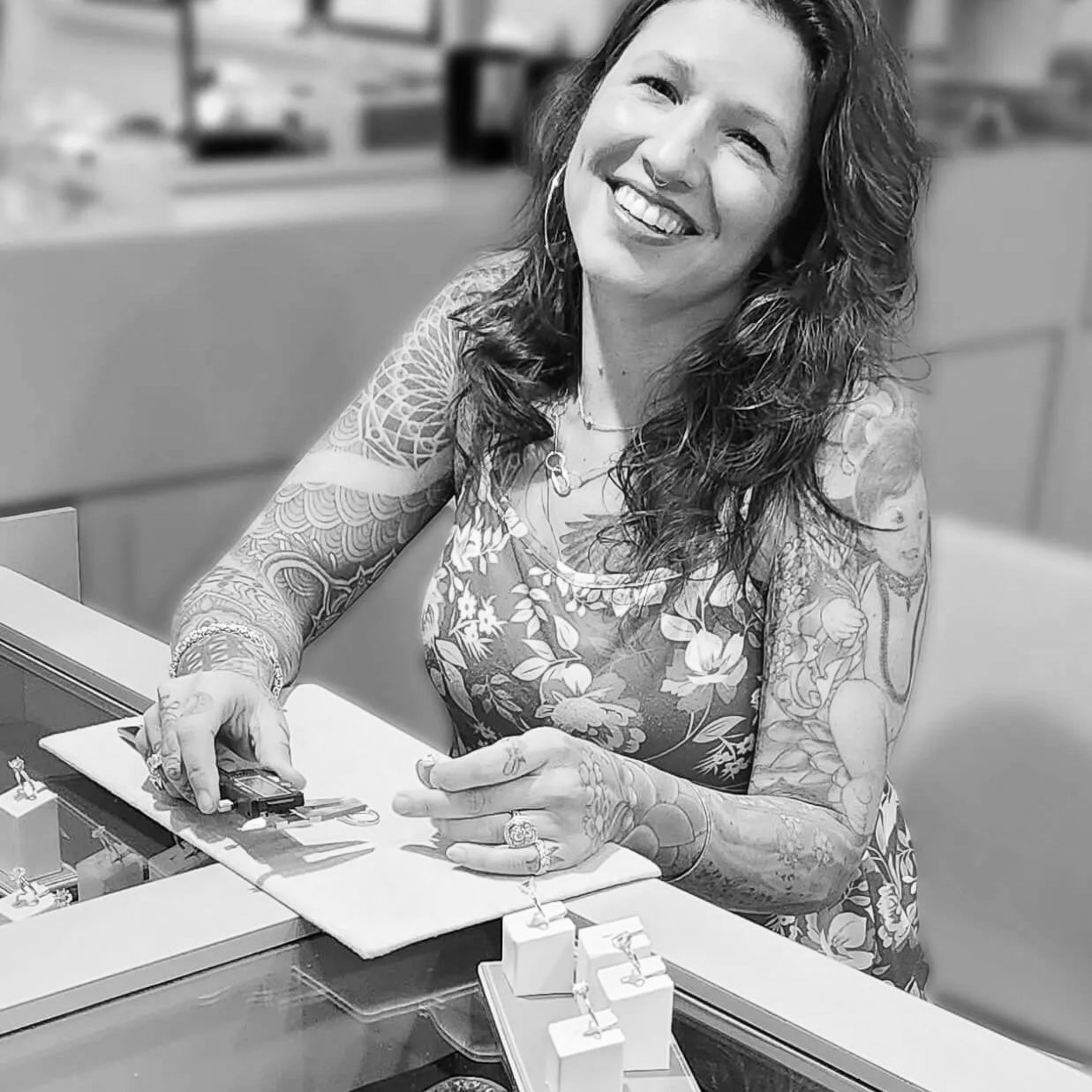 Briana smiles while working behind a jewelry store display case.