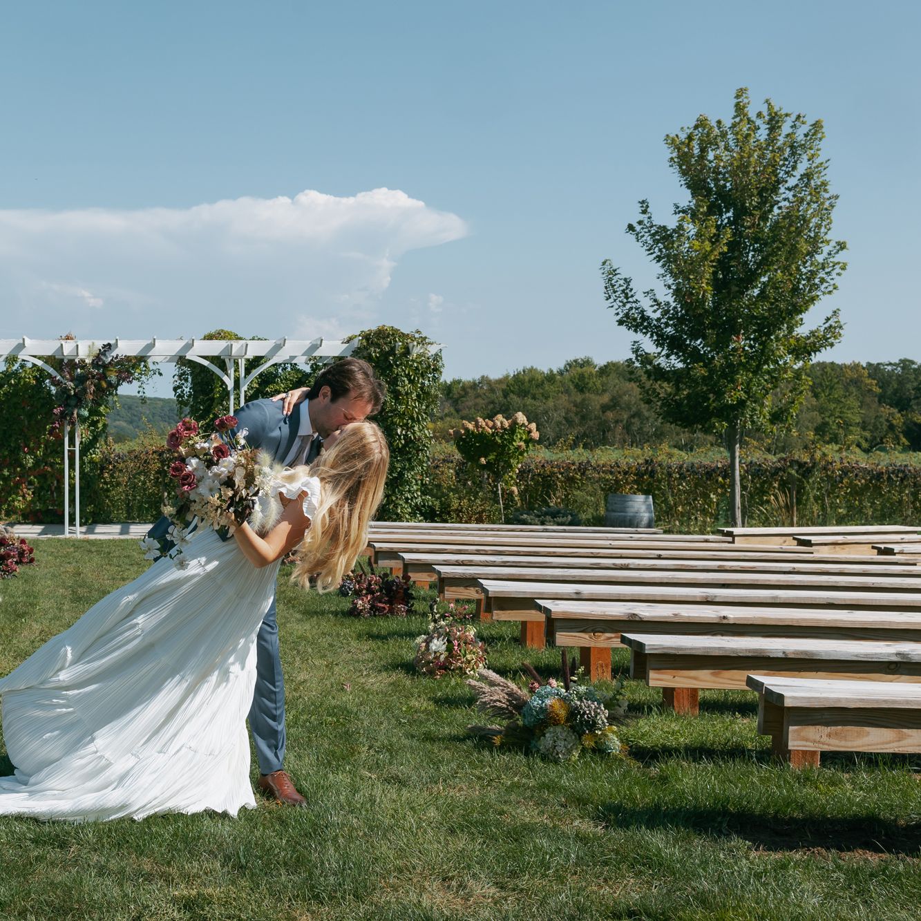 Groom dips bride and they share a kiss at the end of the aisle on the grounds of Rustic Roots Winery