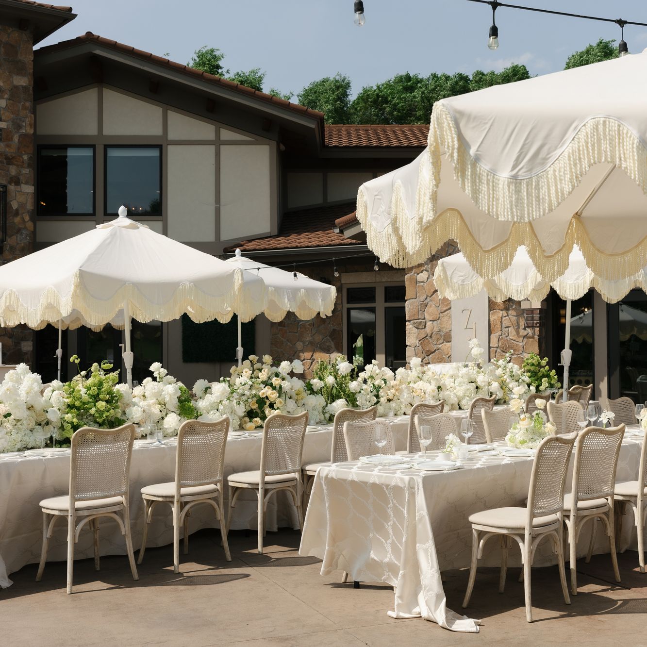 Long tablescapes shaded by soft yellow umbrellas, accented by lush florals in outdoor reception scene at Belle Âme Vineyard