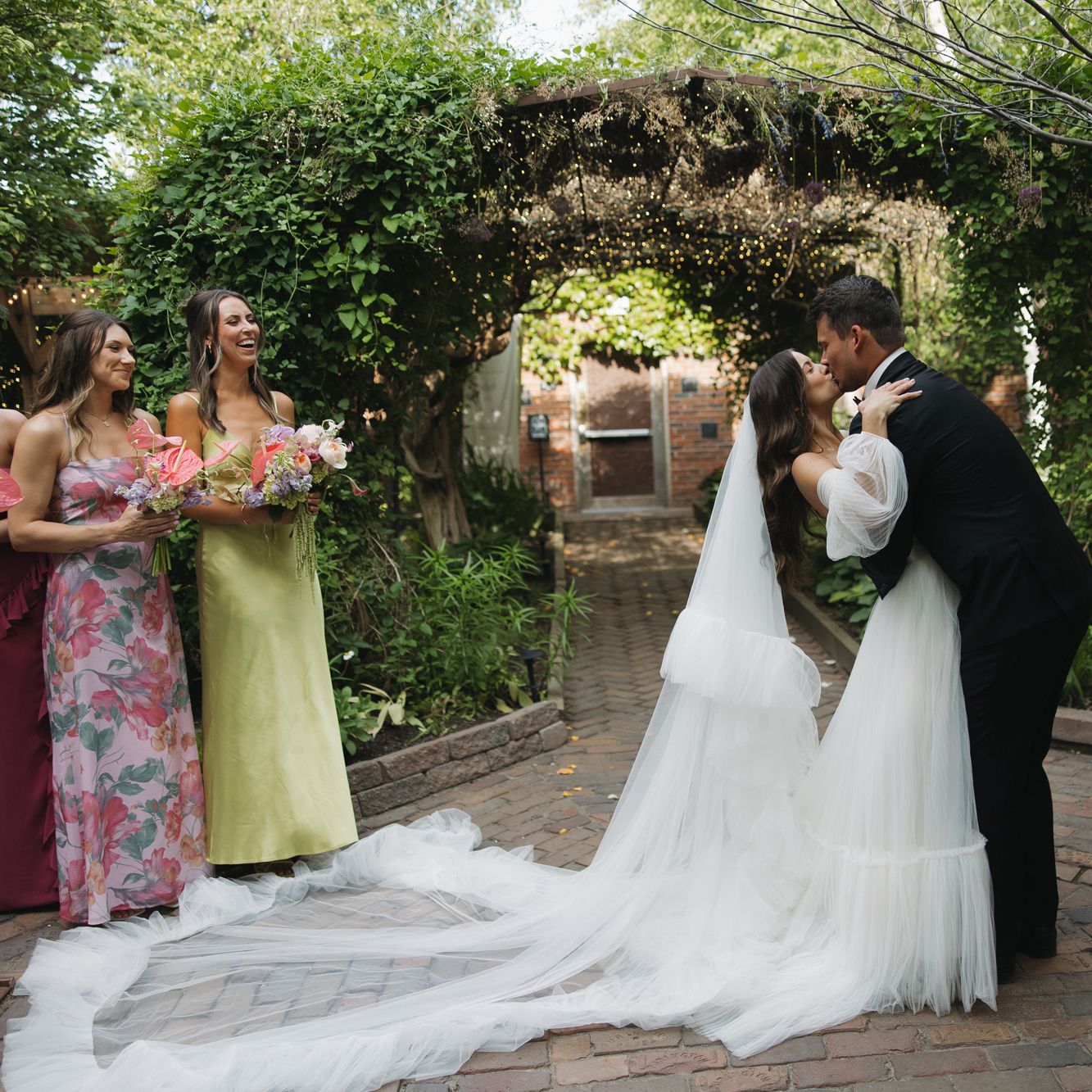 Bride and groom share a kiss after exchanging vows under an ivy trellis at The Bohemian Gardens