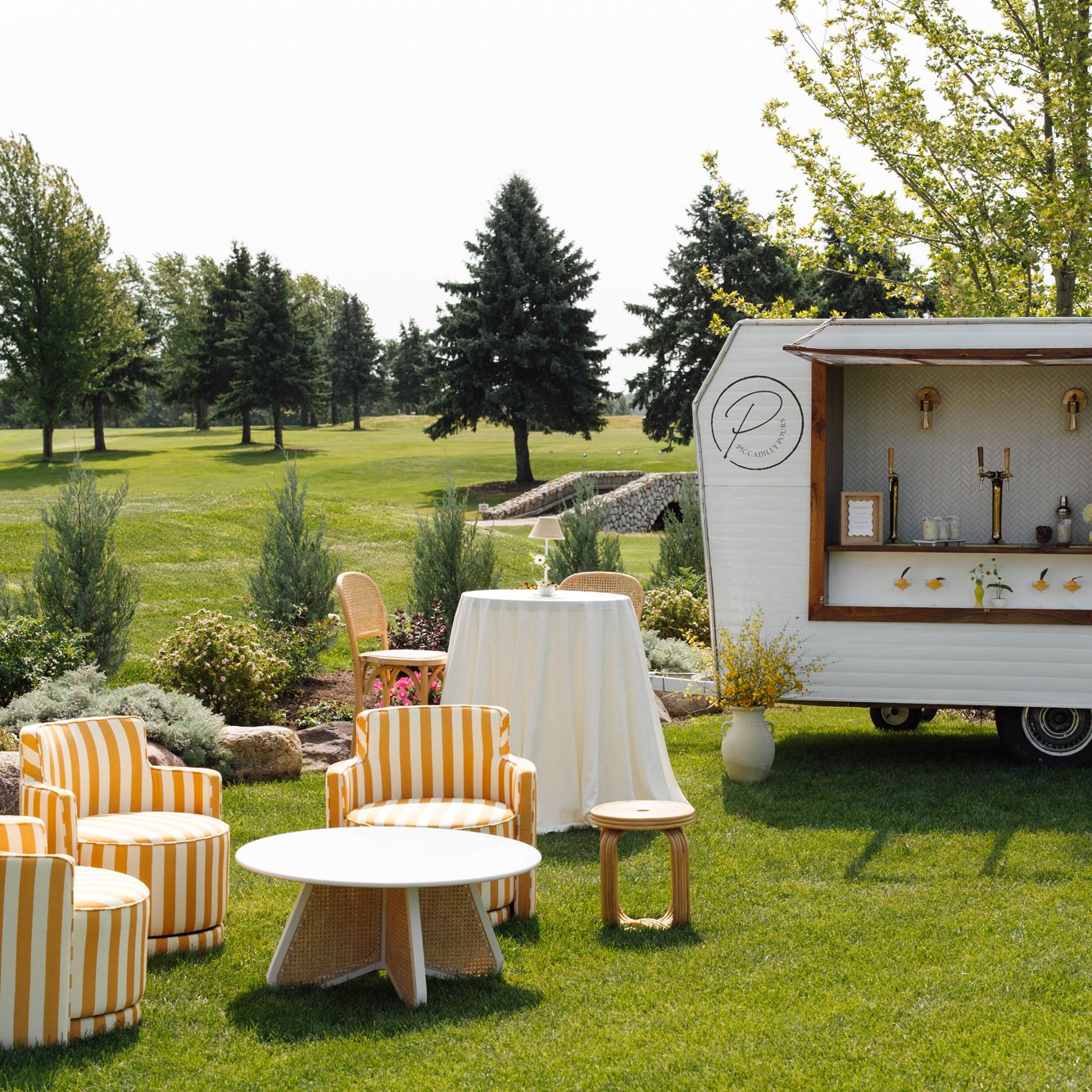 Sunny outdoor happy hour scene with yellow striped furniture and mobile bar at the Wexford at Emerald Greens