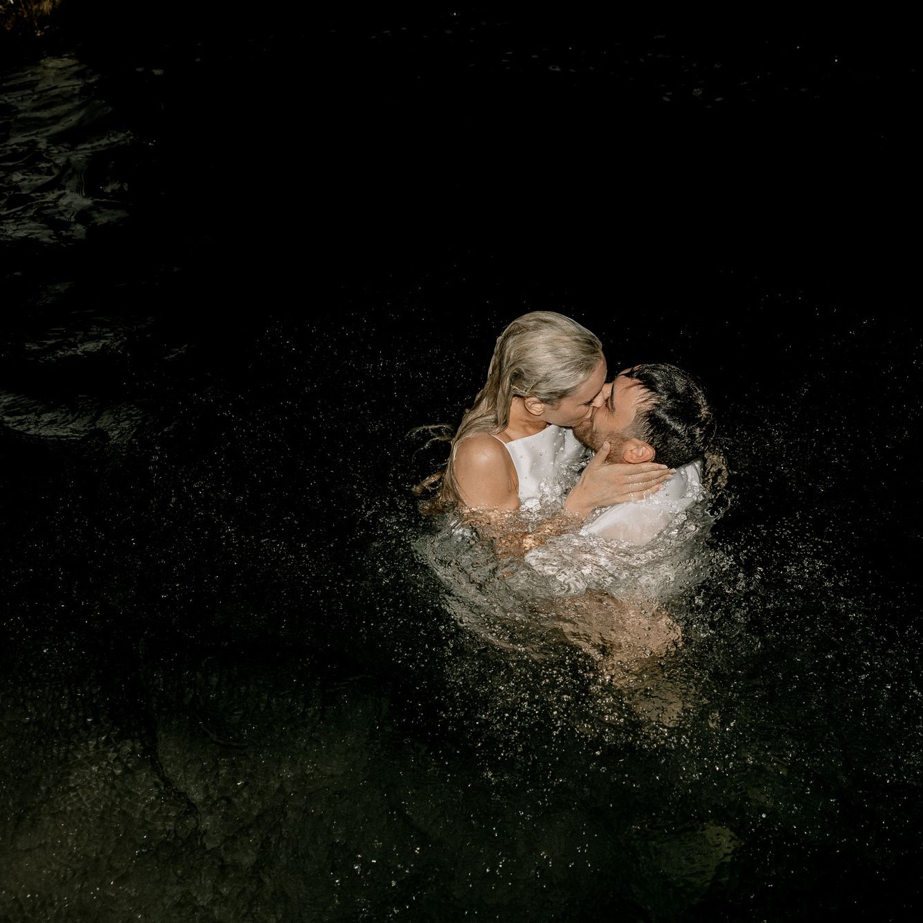 Bride and groom share a kiss in the waters of Lake Geneva in a light night dip in their wedding attire