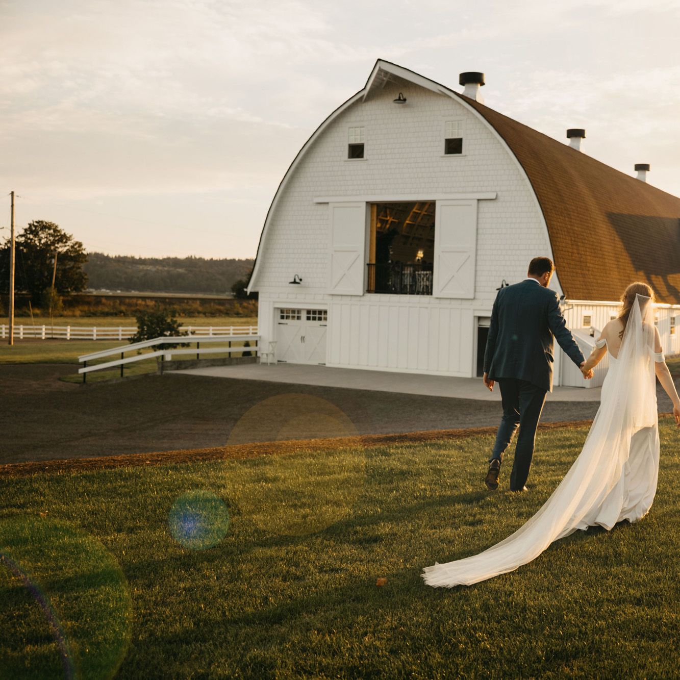 Katie and Connor walk hand in hand on the grounds of Fiddler's Bluff on their wedding day