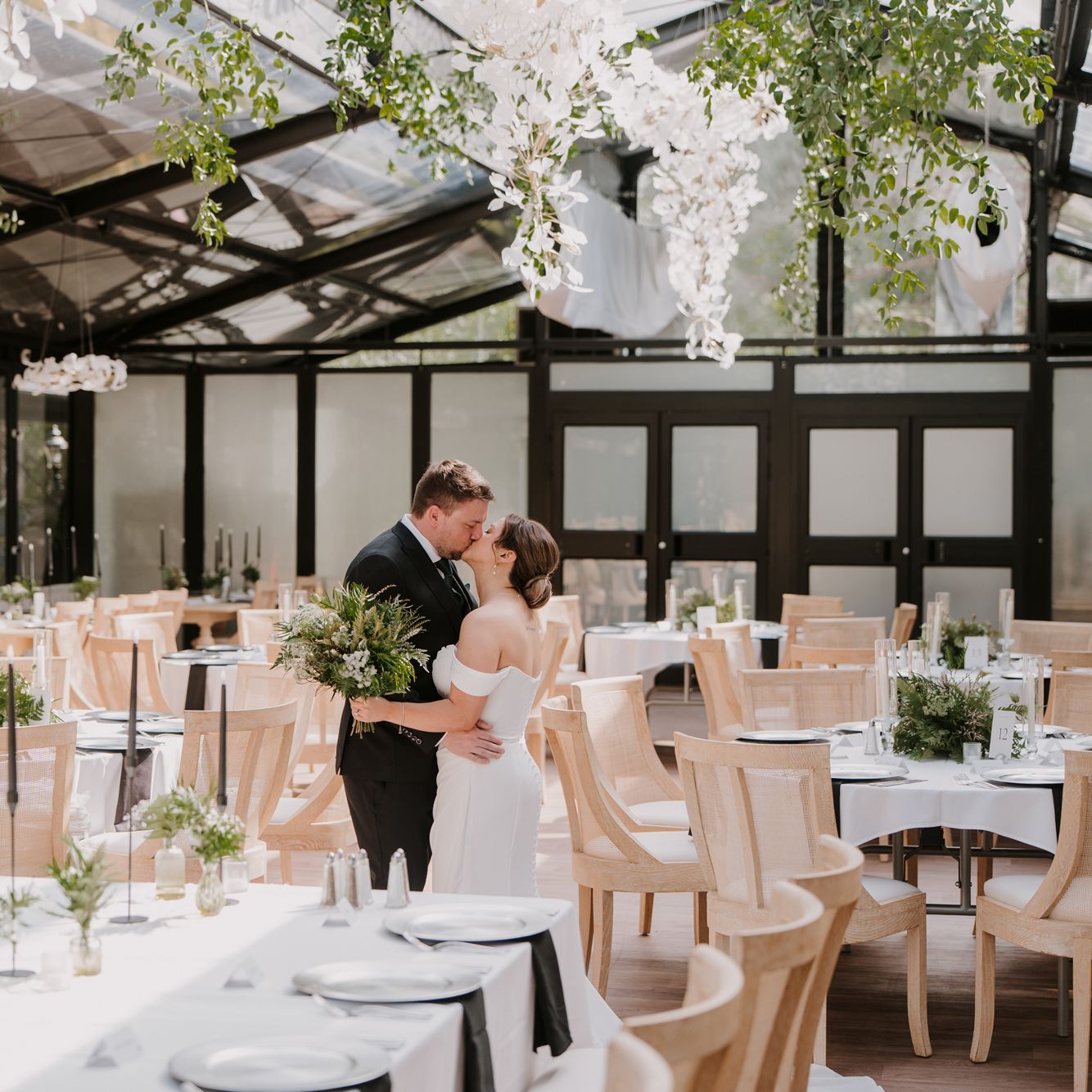 Bride and groom embrace amidst their foliage-forward, modern wedding day at Woodland Glasshouse