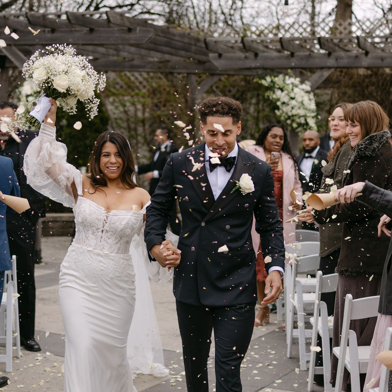 Bride and groom walk back down the aisle after exchanging vows, celebratory petals raining over them at The Ivy House