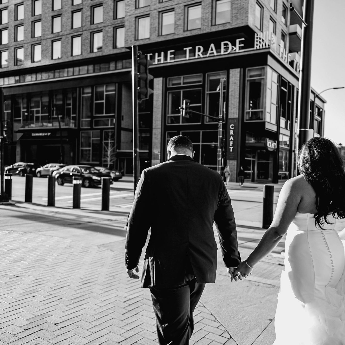Bride and groom hold hands as they cross the street to the Trade Hotel