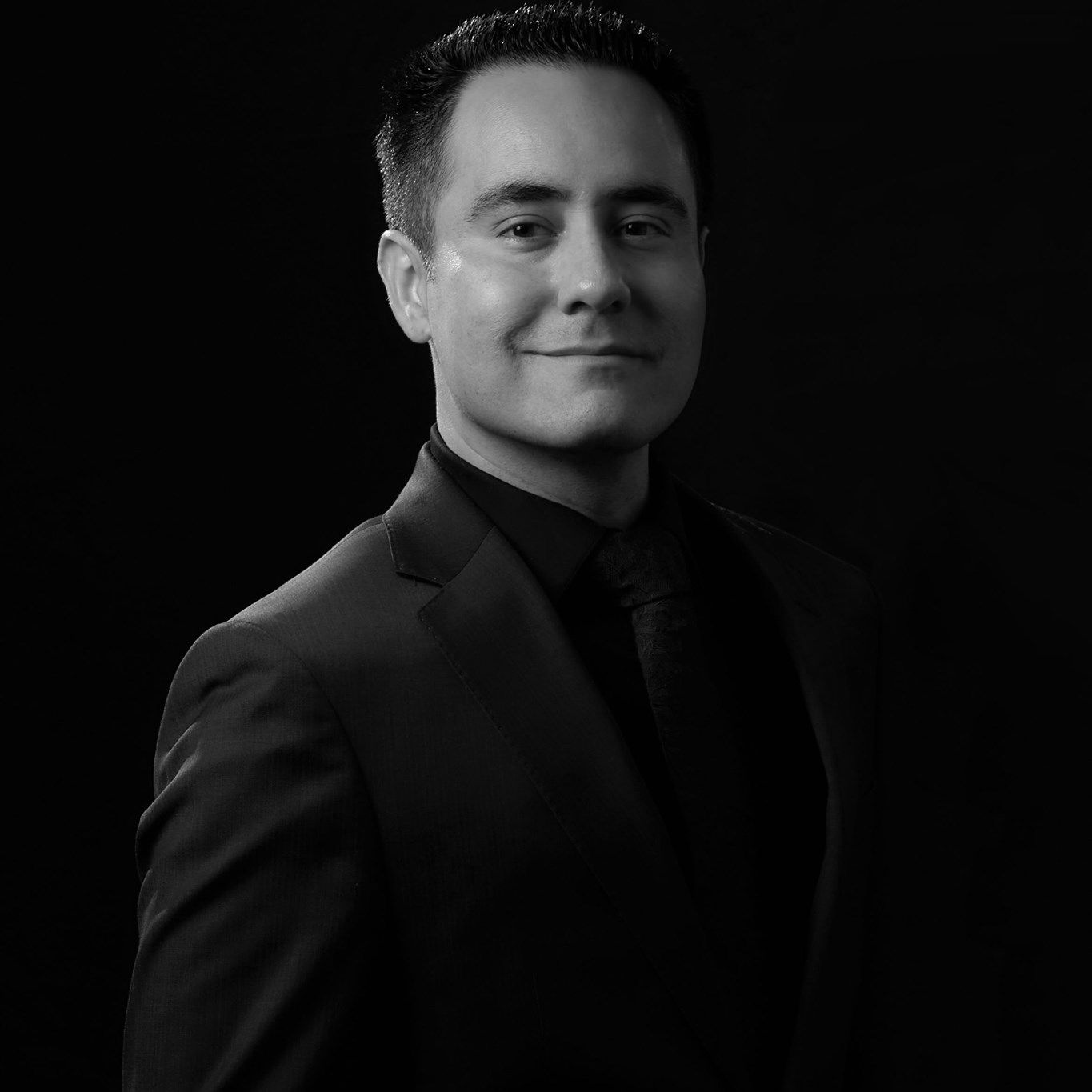Professional black-and-white portrait of Richard Saenz of Royal Films in a suit against a dark background