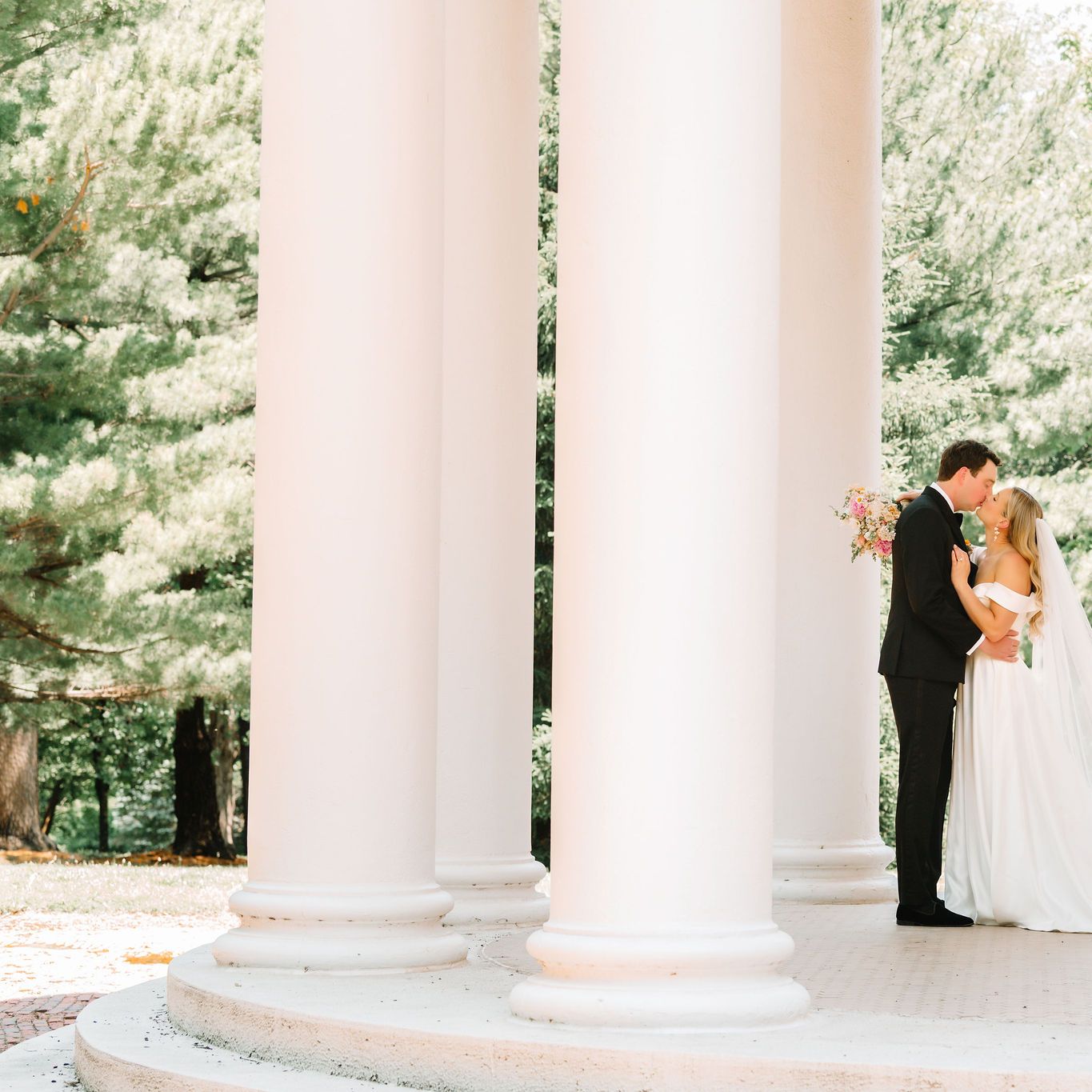Bride and groom embrace in stone gazebo in wedding day at Arbor Day Farm