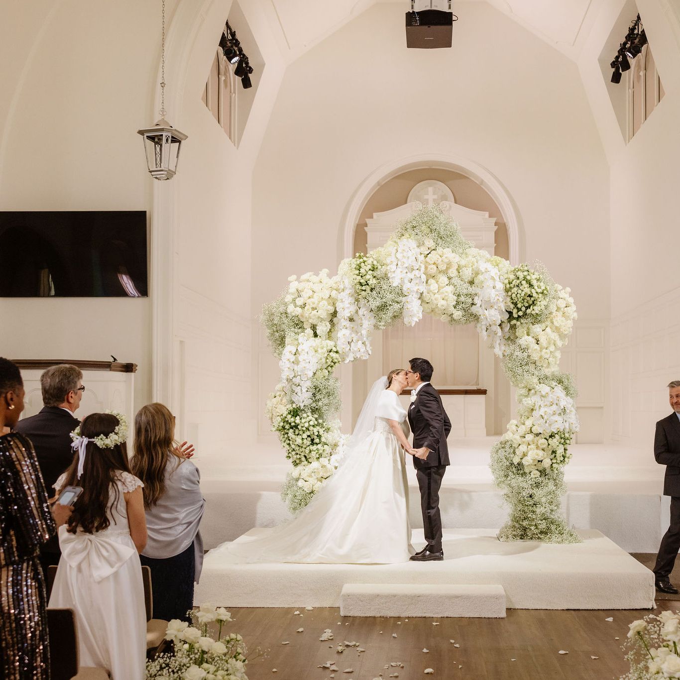 NBC Southern California newscaster Ted Chen shares a first kiss with his bride, Ariell Kirylo, under a breathtaking white floral arch at Vintage Church in Los Angeles.
