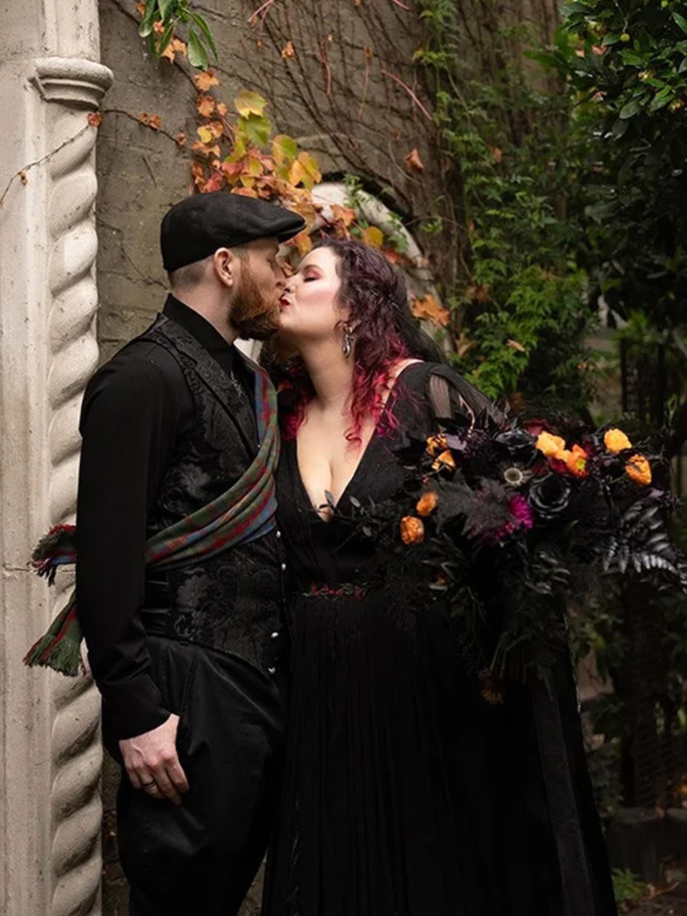 A close portrait of Paige and Dylan kissing beneath The Corson Building’s arched entrance, with pumpkins decorating the steps.