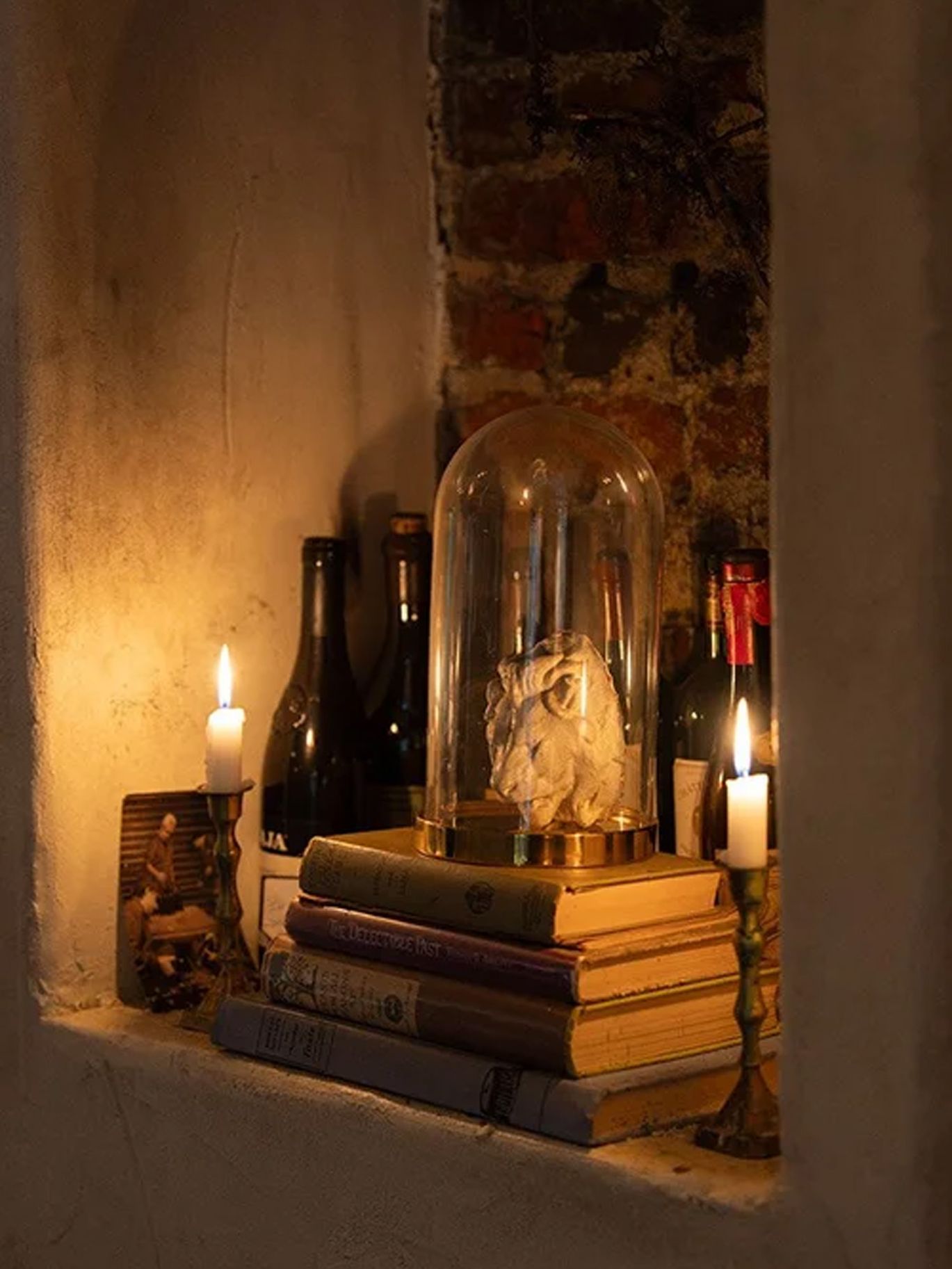 A skull under a glass cloche sits atop vintage books between candles at the couple’s Halloween wedding reception.