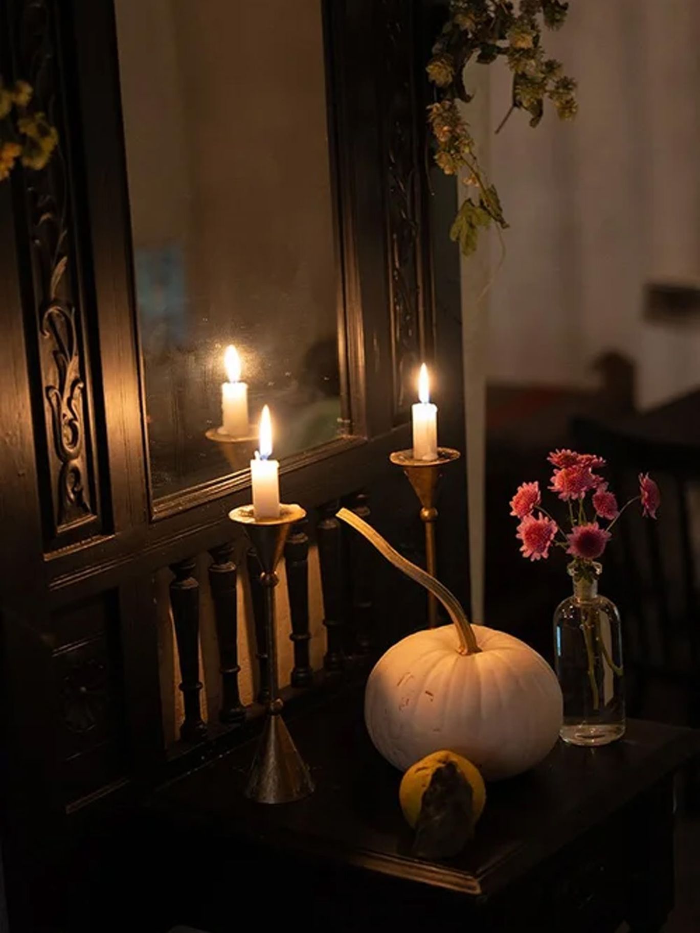 Lit candles, a white pumpkin and flowers decorate a mantel at Paige and Dylan’s Halloween wedding reception.