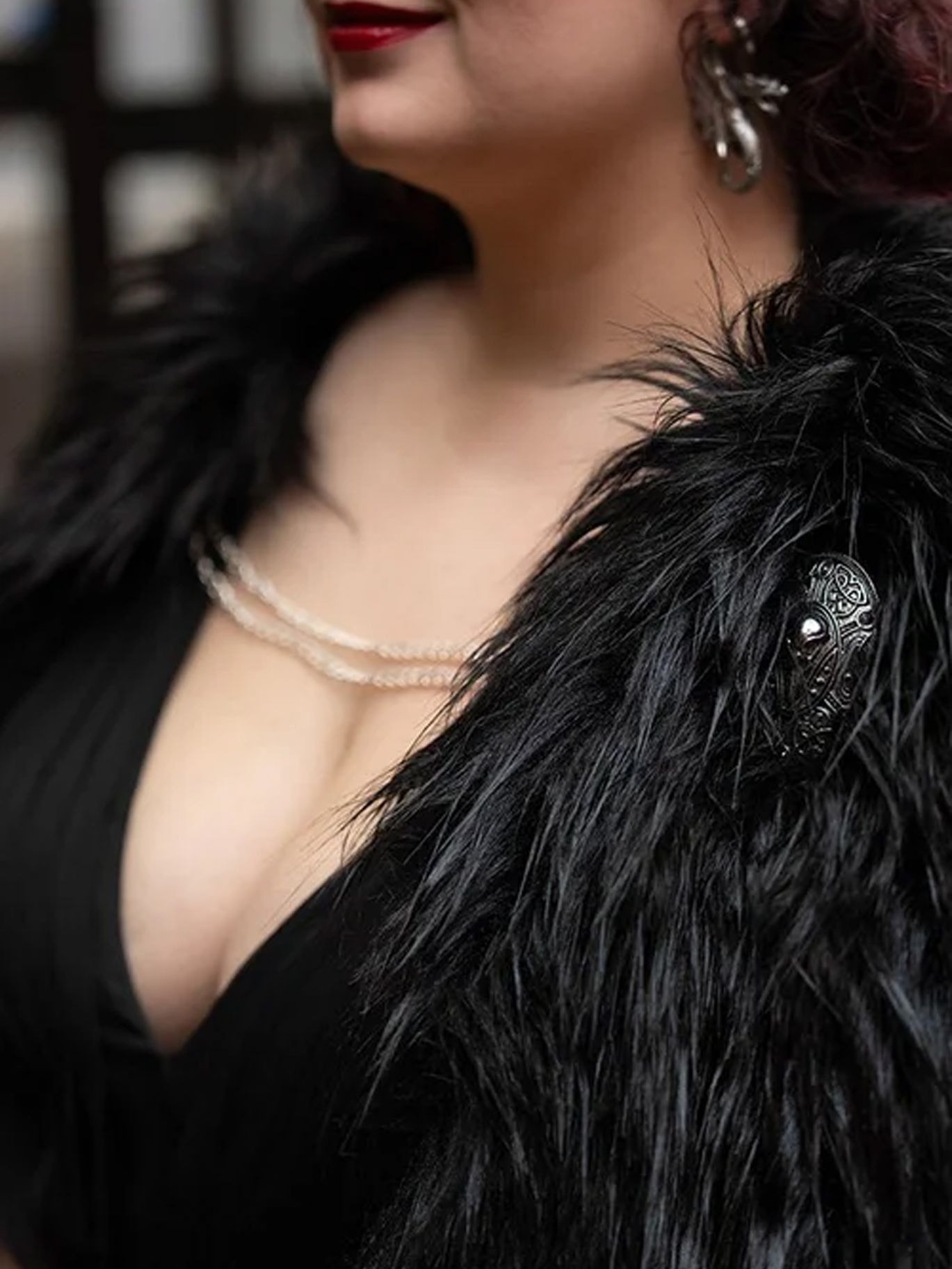 A close-up of the bride’s jewelry and black feather wrap at her Halloween wedding.