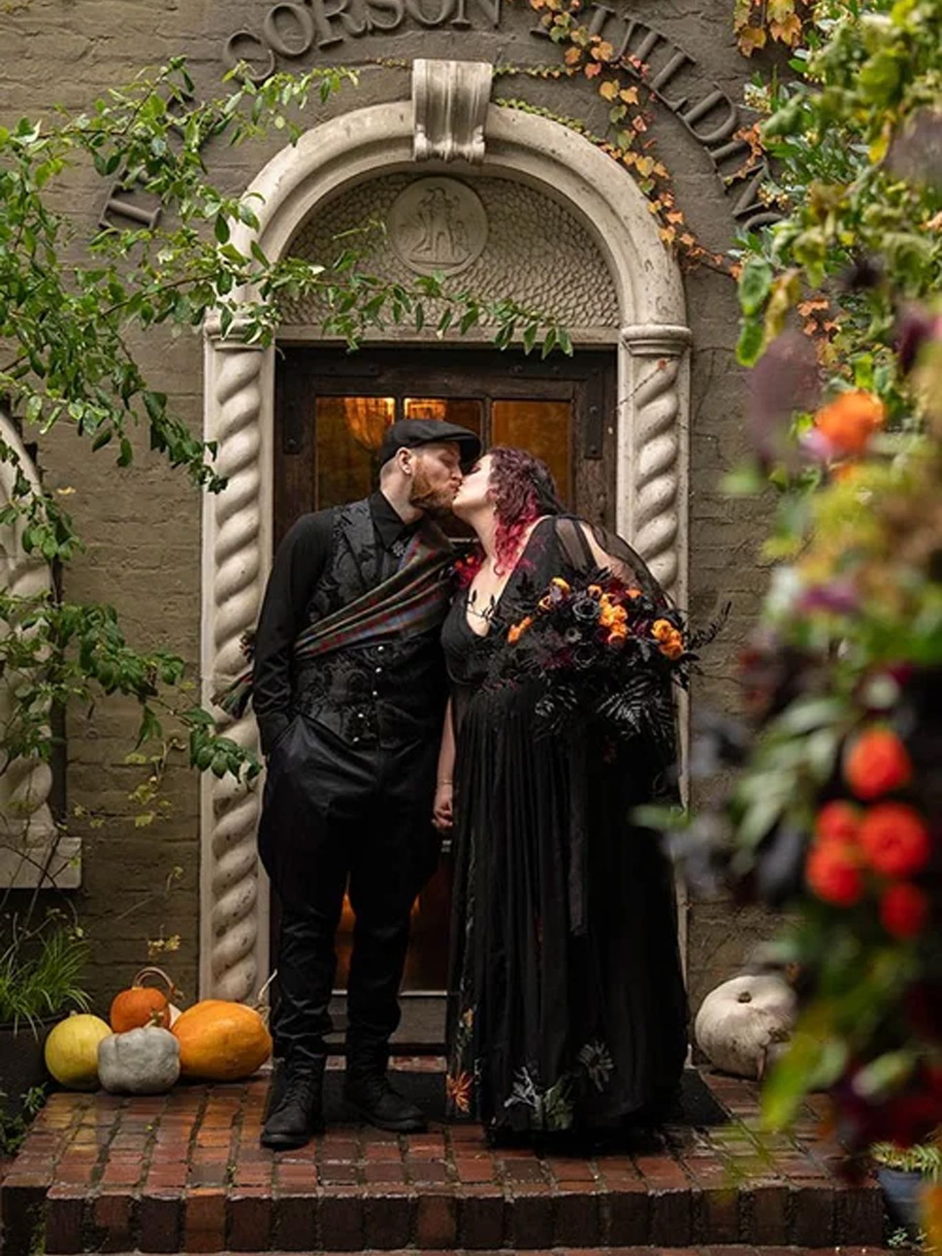 Paige and Dylan kiss in the doorway of The Corson Building during their Seattle Halloween wedding.