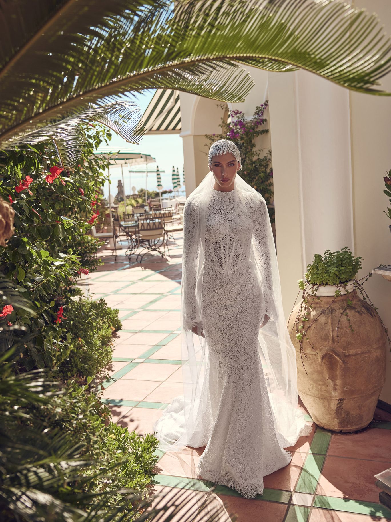 Ricca Sposa Couture Couture Capri Fall 2027 high-neck lace wedding dress with long sleeves, fitted silhouette and sheer bridal veil.