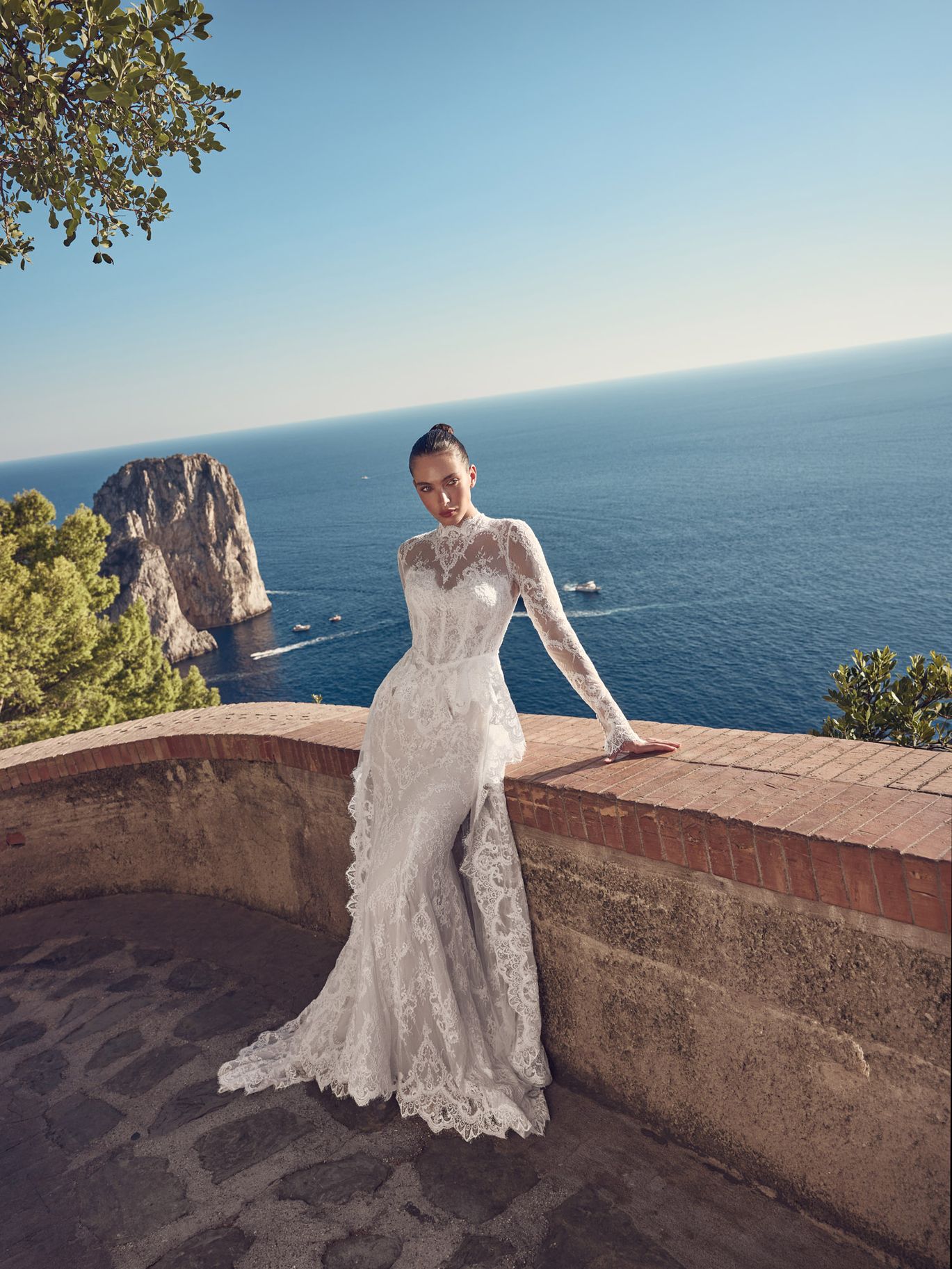 Ricca Sposa Couture Fall 2027 Couture Capri fitted lace wedding gown with a high neckline, sheer long sleeves and floral lace detailing.