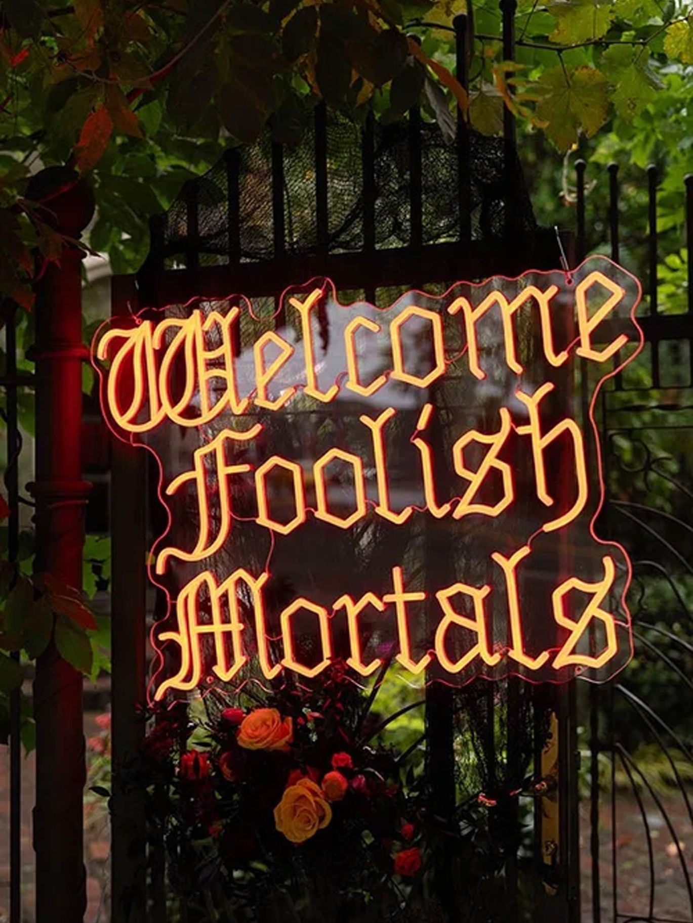 An illuminated “Welcome Foolish Mortals” sign marks the entrance to Paige and Dylan’s Halloween wedding.
