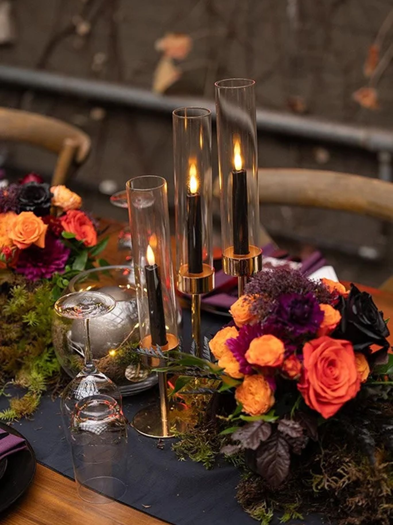 Black candles, orange and purple flowers, and glassware decorate a reception table at the Seattle Halloween wedding.