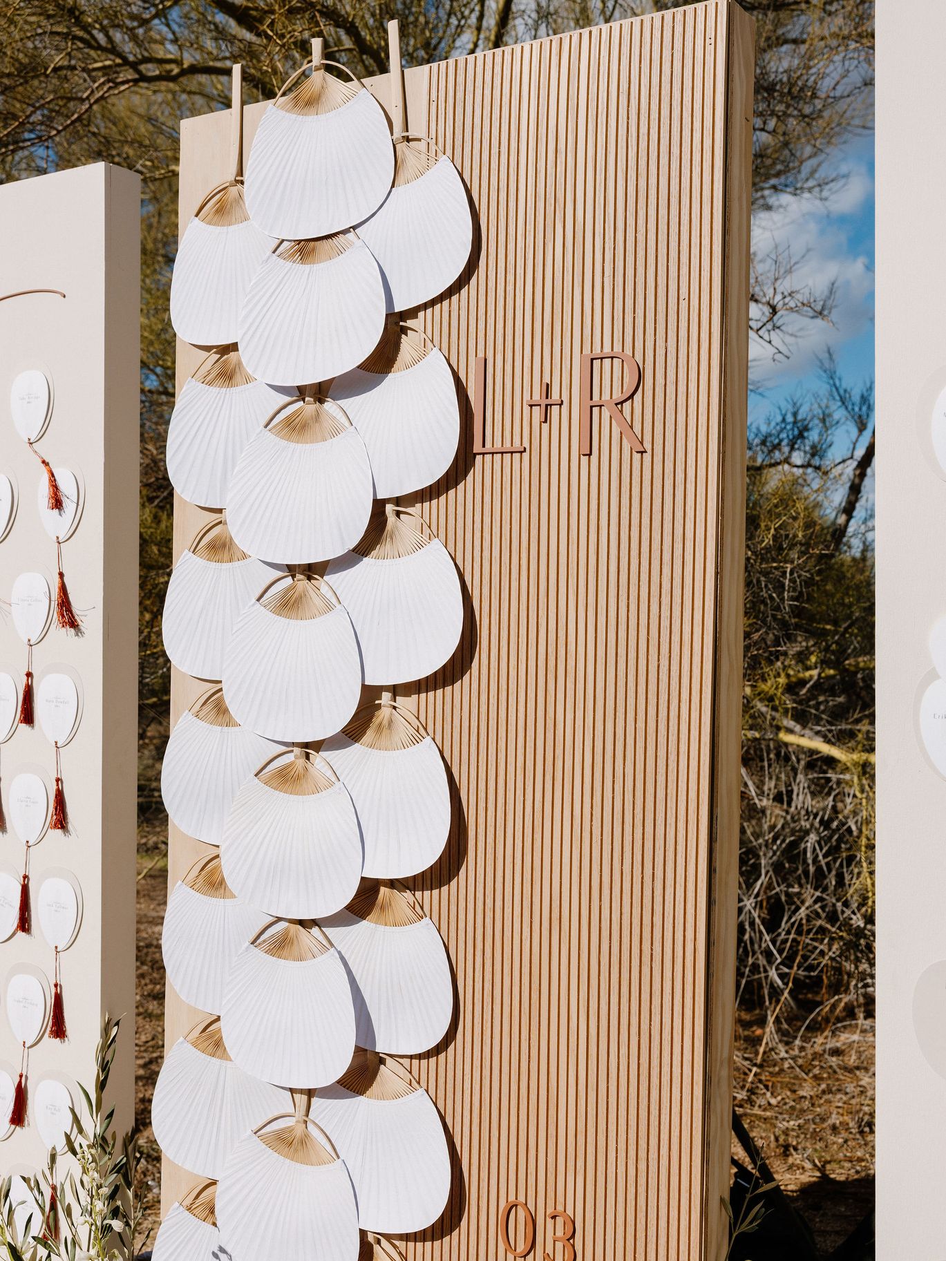 Close-up of a wood wedding display decorated with layered white fans and the couple's initials