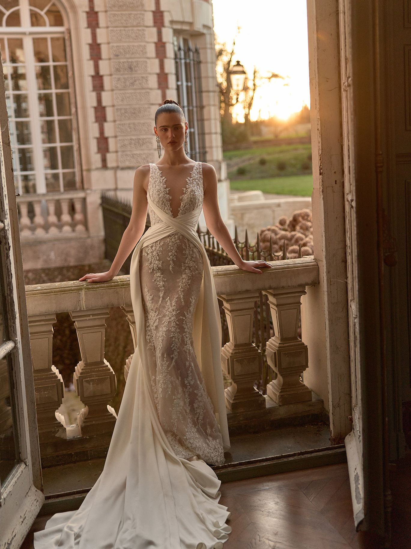 WONA Concept Reverie wedding dress with an off-the-shoulder corset, lace sleeves and layered draped overskirt, featured in a romantic draping trend roundup.