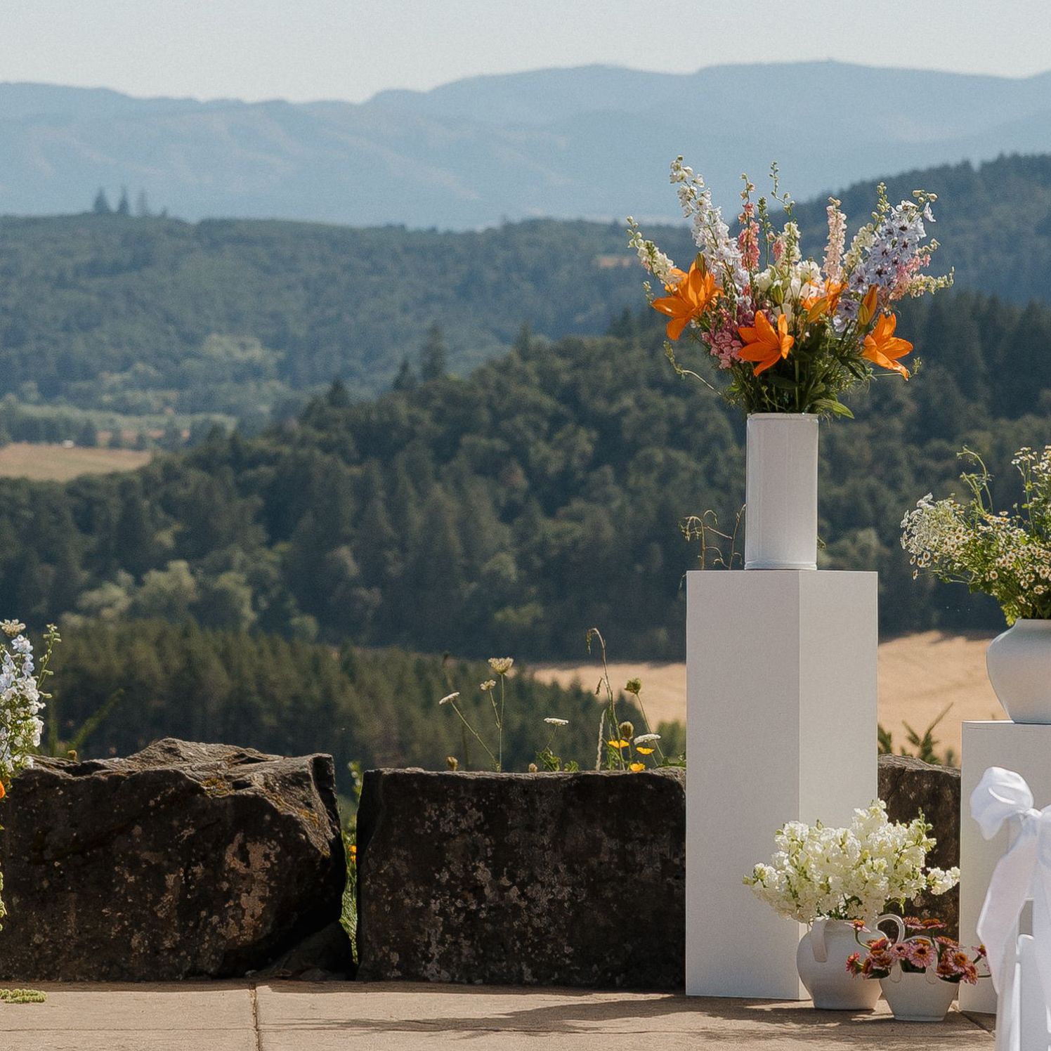 Modern altar featuring vivid blooms on podiums against the scenic views of Youngberg Hill Inn & Winery