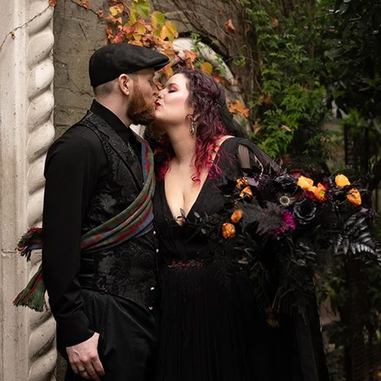 A close portrait of Paige and Dylan kissing beneath The Corson Building’s arched entrance, with pumpkins decorating the steps.