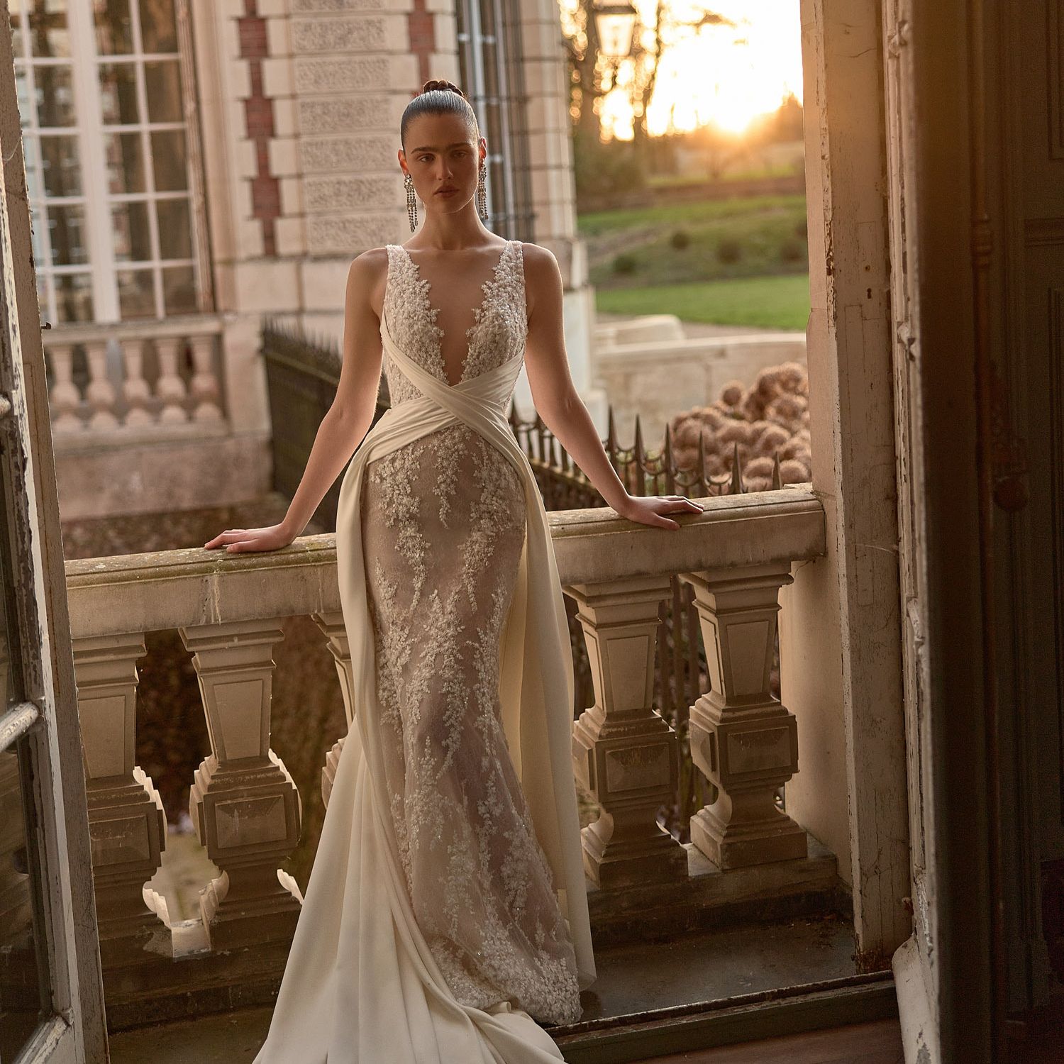 WONA Concept Reverie wedding dress with an off-the-shoulder corset, lace sleeves and layered draped overskirt, featured in a romantic draping trend roundup.