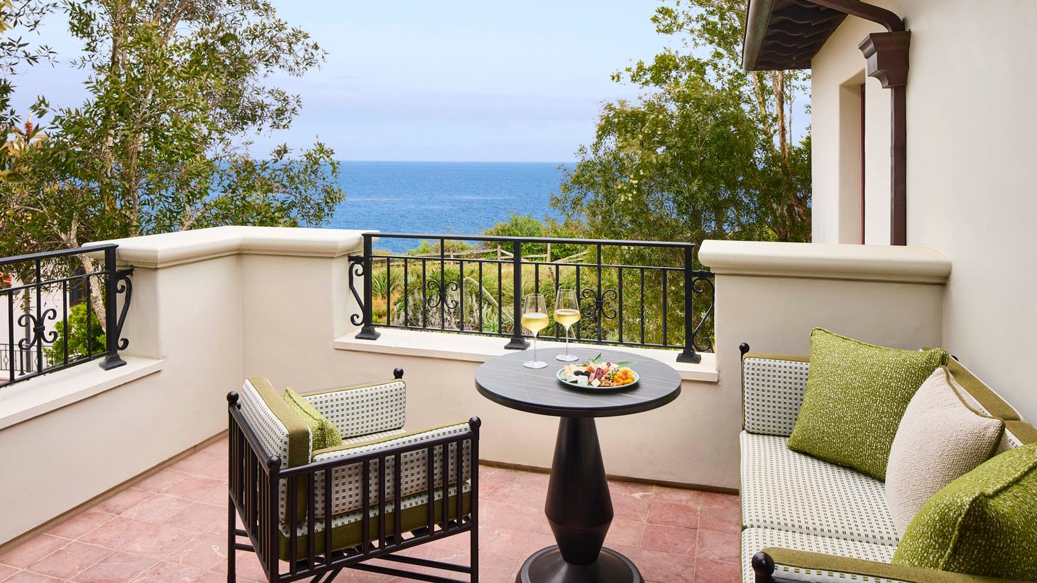 An ocean-view suite balcony at The Ritz-Carlton Bacara, Santa Barbara features lounge seating and a table set for two overlooking the Pacific