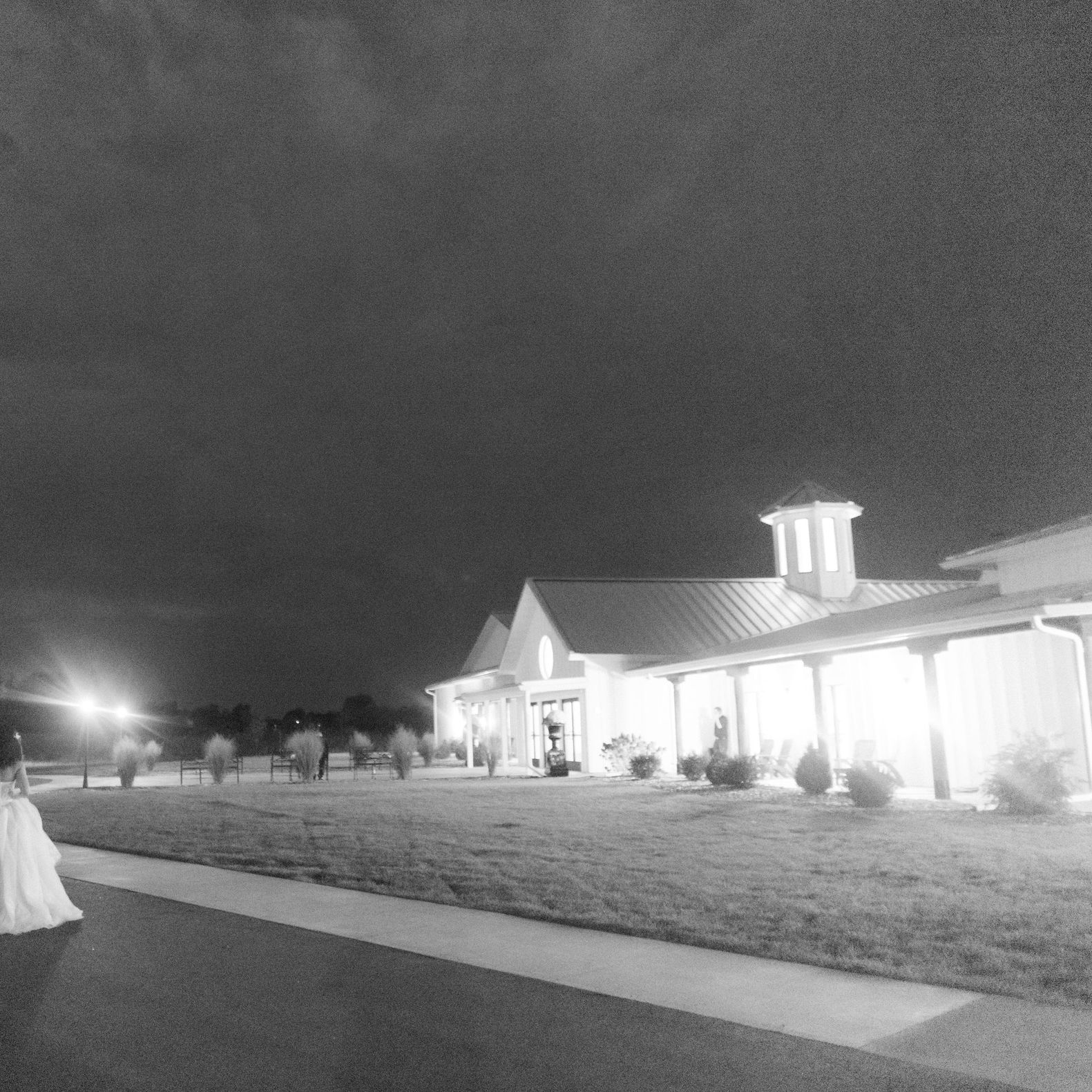 Grainy black and white photo of the bride and groom in front of modern venue