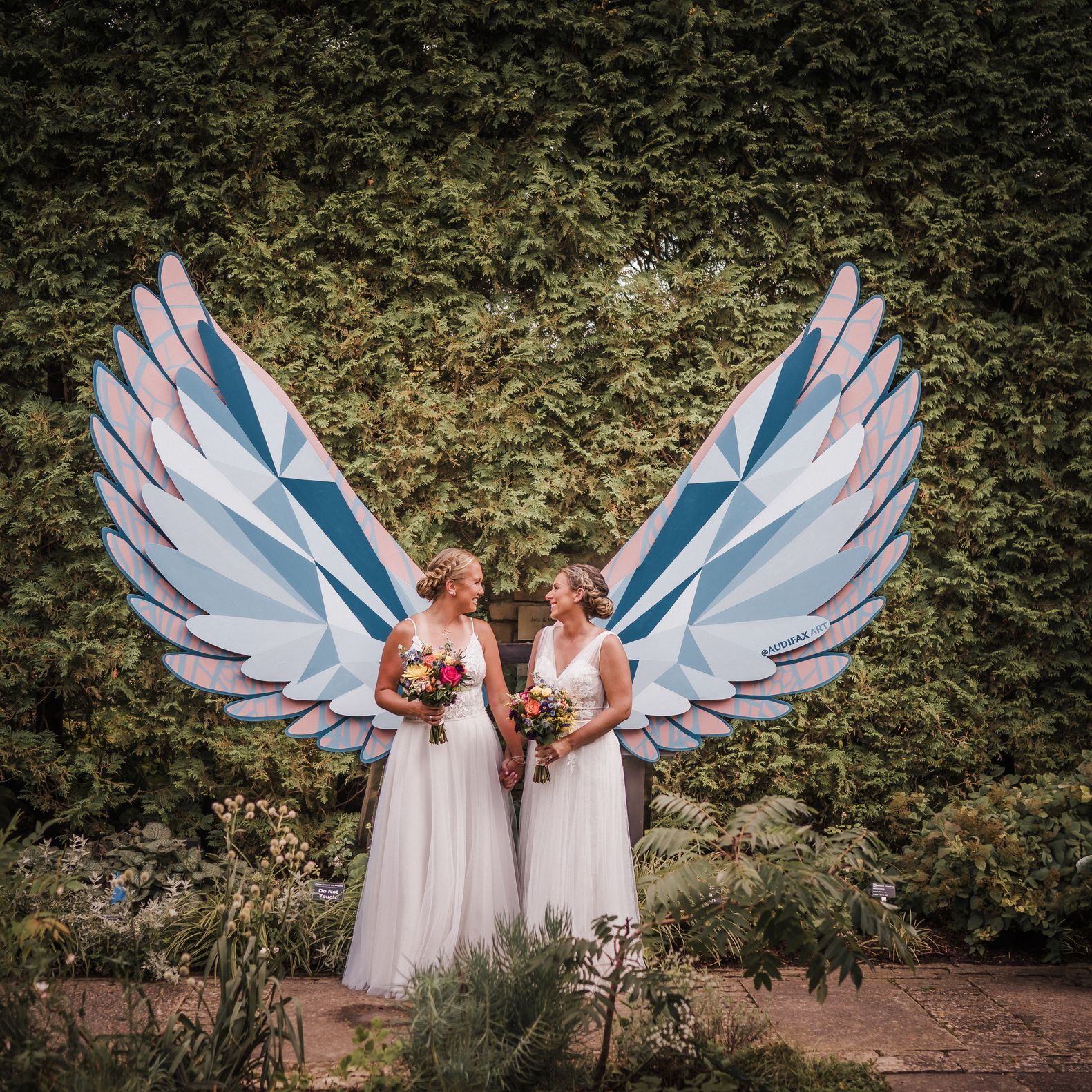 Brides stun in coordinating wedding attire amongst lush greenery