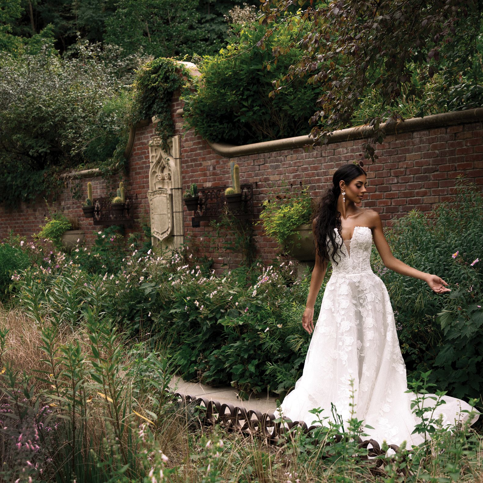 Model Kami Buchanan poses in a strapless lace gown against the verdant backdrop of the Lauritzen Gardens