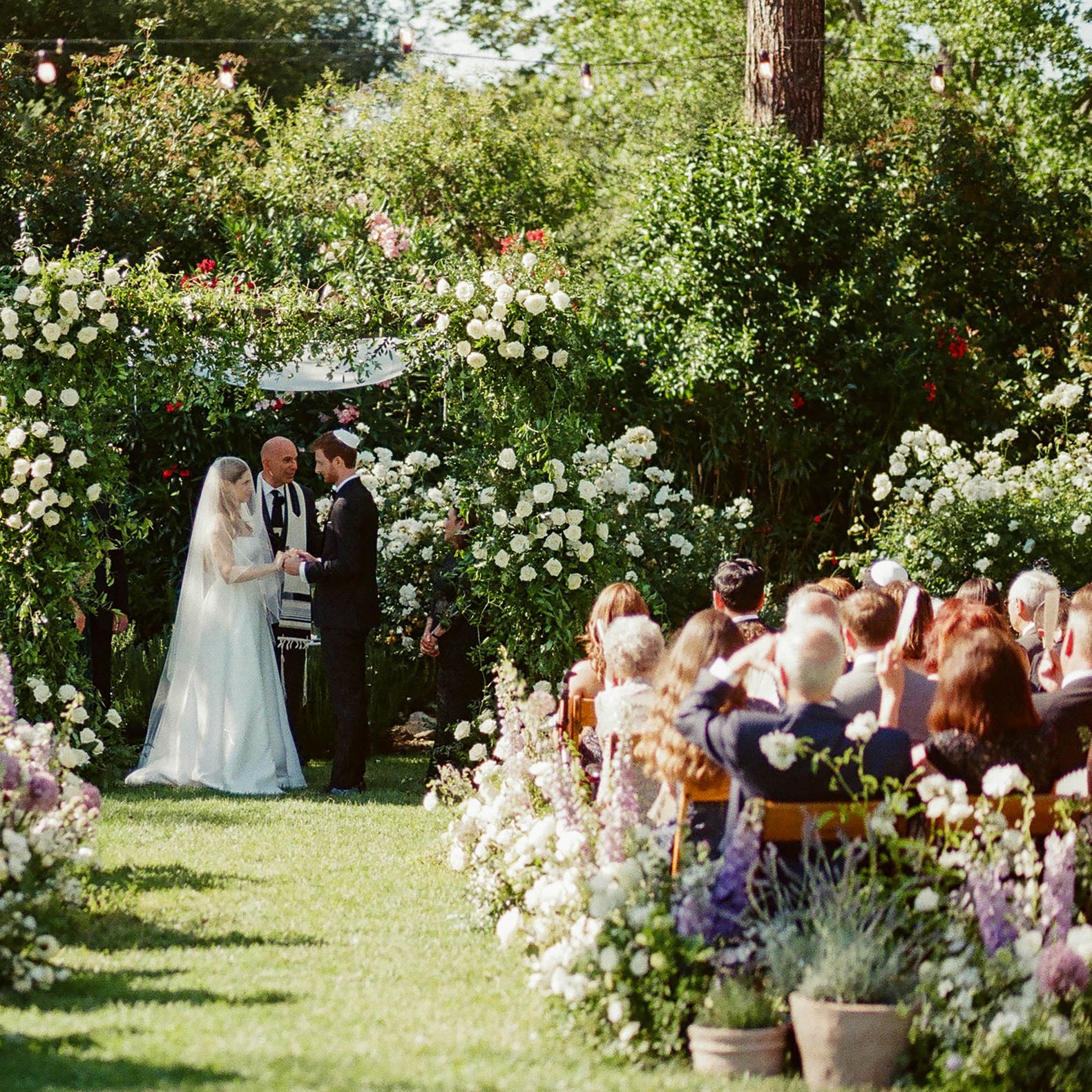 Bride and groom stand under chuppah during enchanted garden wedding ceremony at The Lodge at Malibou Lake