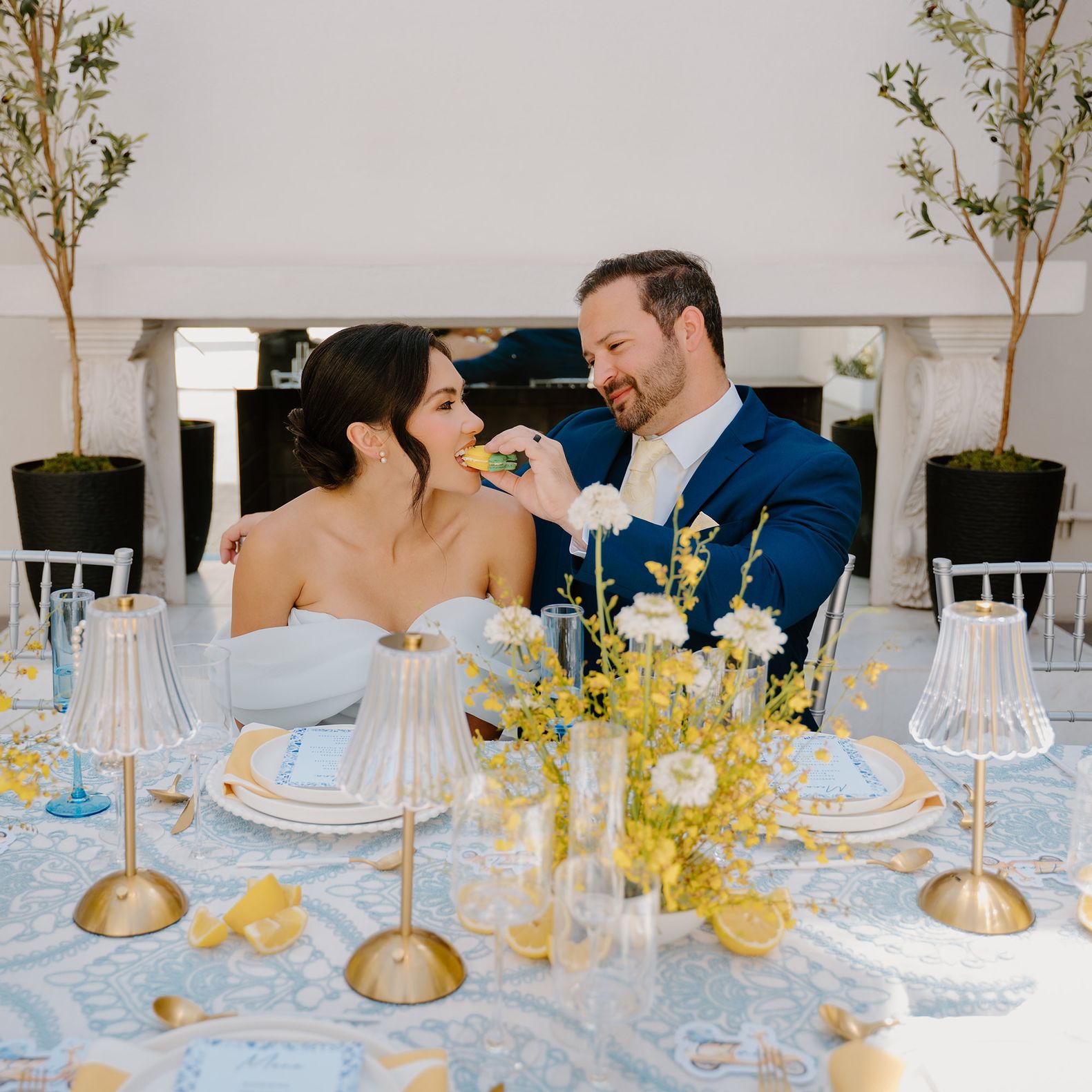 Groom feeds bride a lemon shaped macaron at an Amalfi Coast inspired tablescape