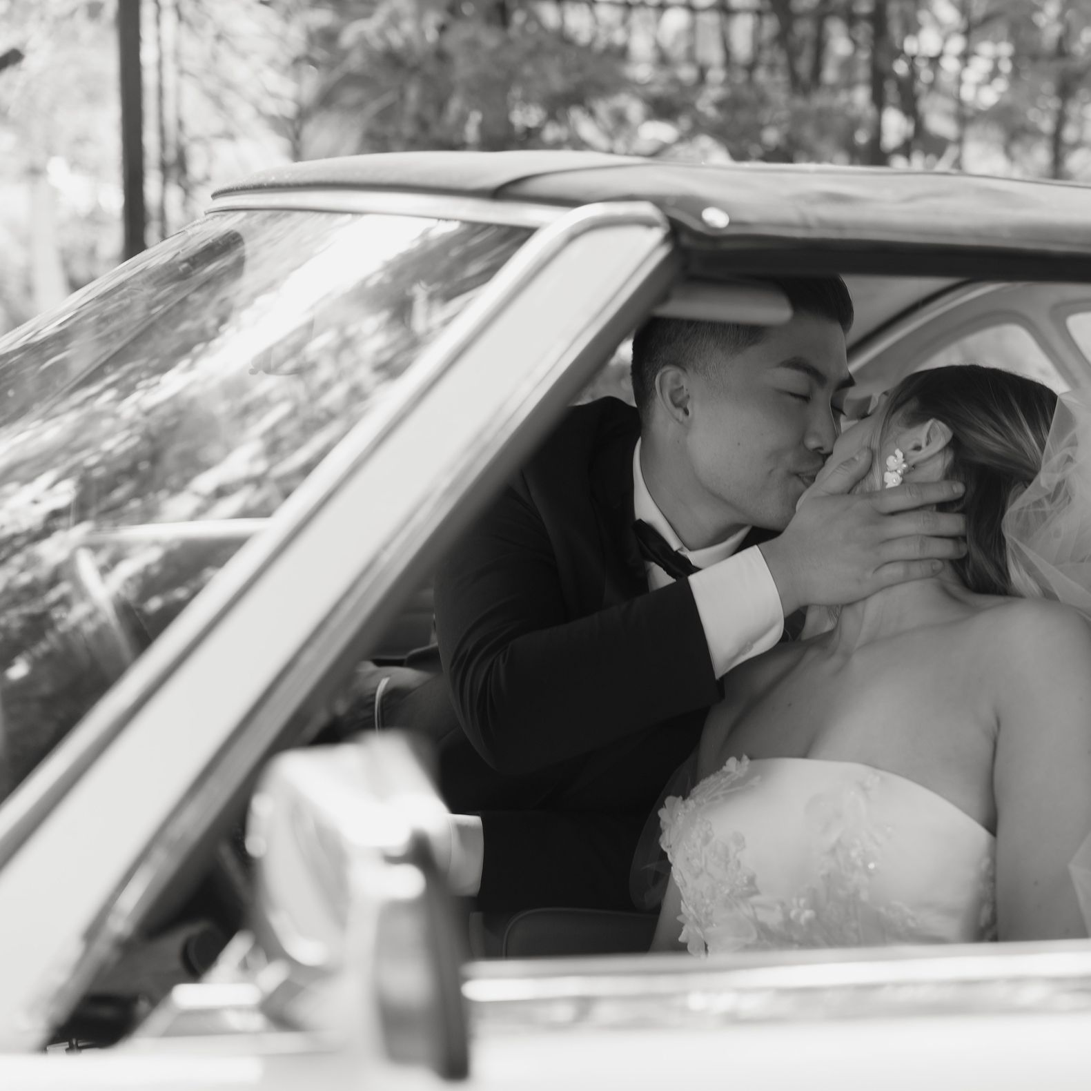 Bride and groom share a kiss inside a vintage car on their wedding day