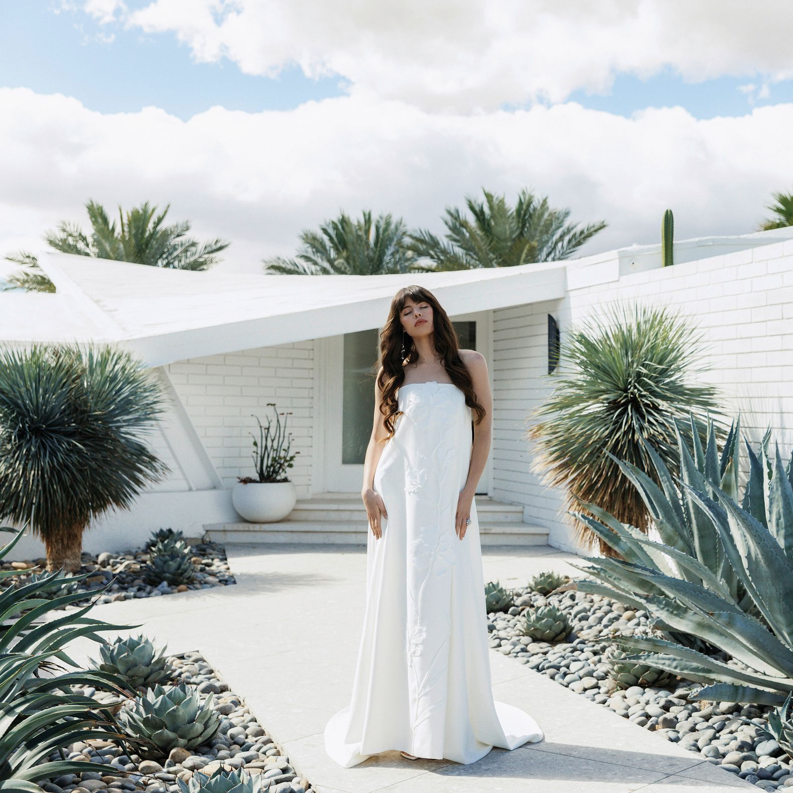 Model poses in front of Desert White House in strapless wedding dress with subtle floral details